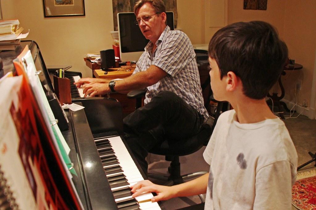 mężczyzna uczący chłopca gry na pianinie