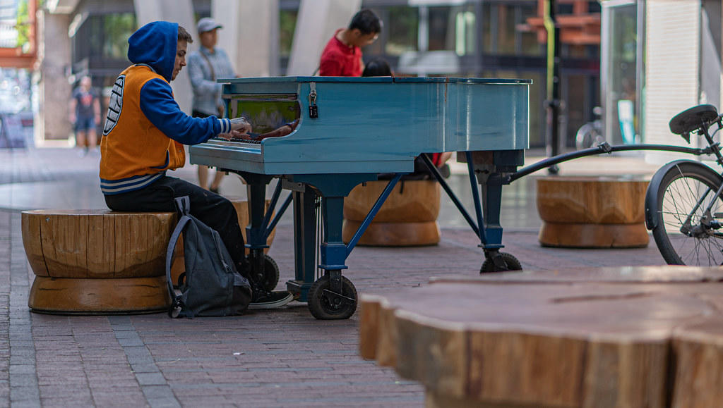 mężczyzna grający na mobilnym fortepianie na ulicy