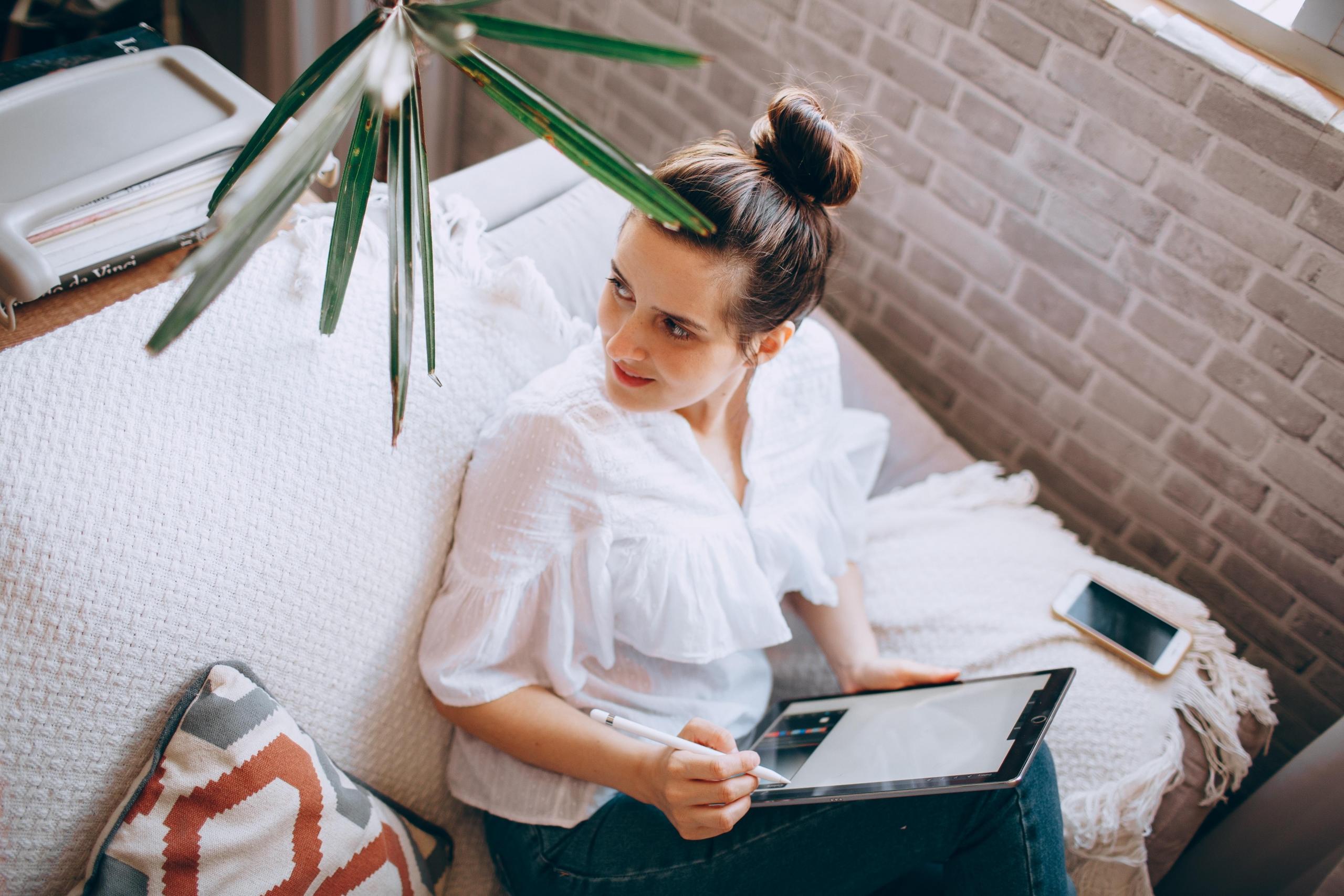 Kobieta siedząca na kanapie z tabletem na kolanach.