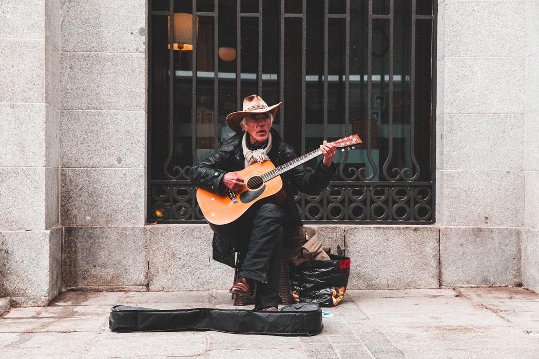 Starszy mężczyzna w kapeluszu grający na gitarze w Madrycie