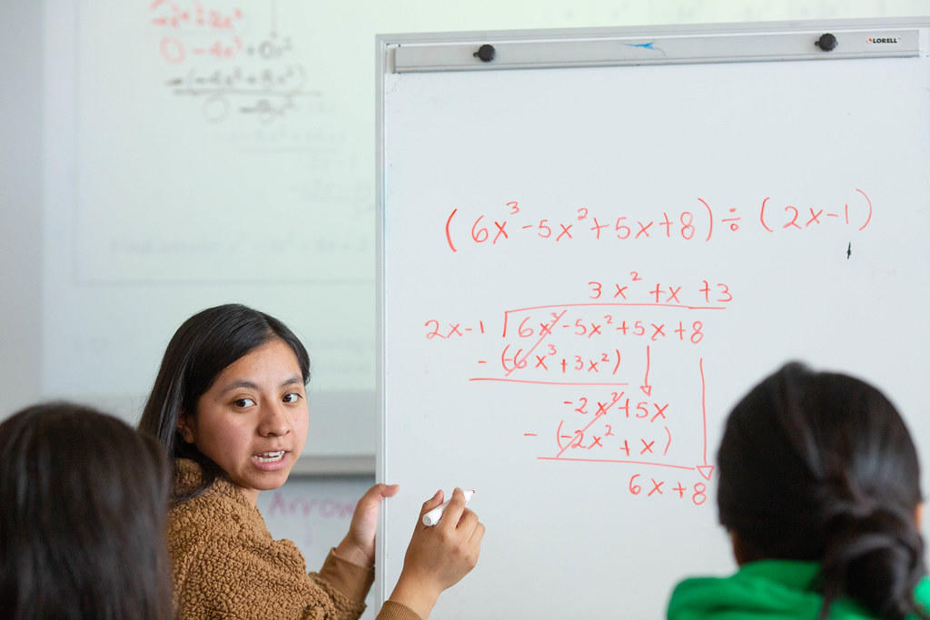 kobieta tłumacząca przy tablicy zagadnienie z matematyki