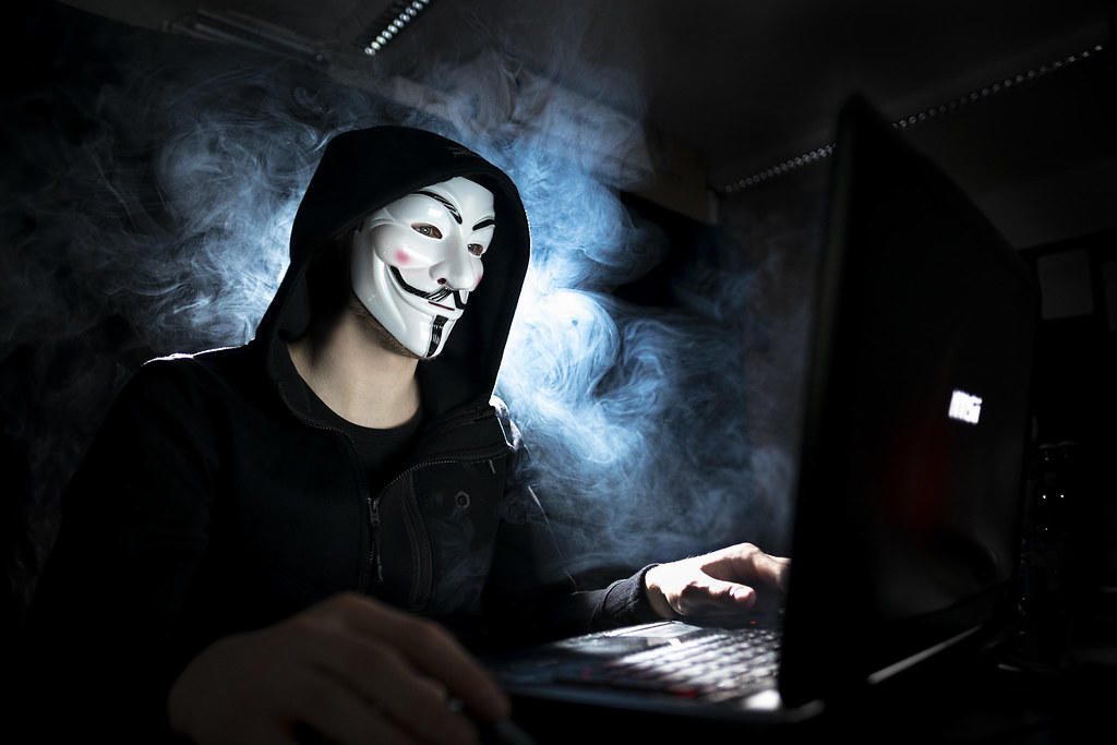 haker przy komputerze w masce anonymous