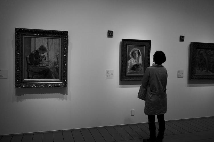 Kobieta oglądająca portrety w galerii sztuki
