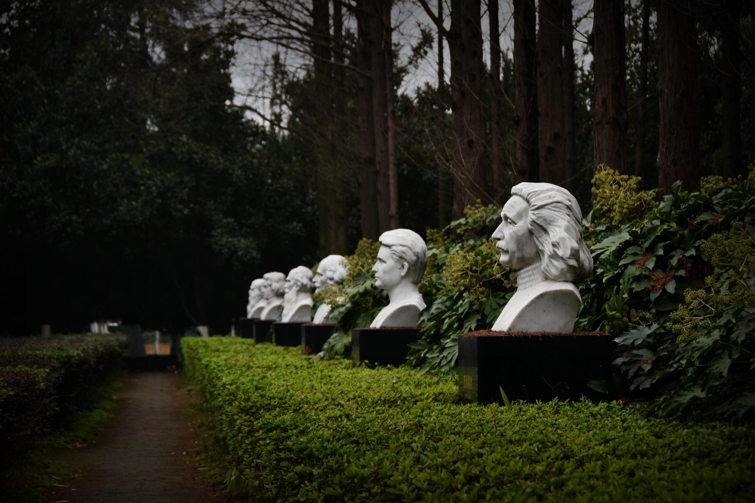 Białe popiersia fizyków w parku.