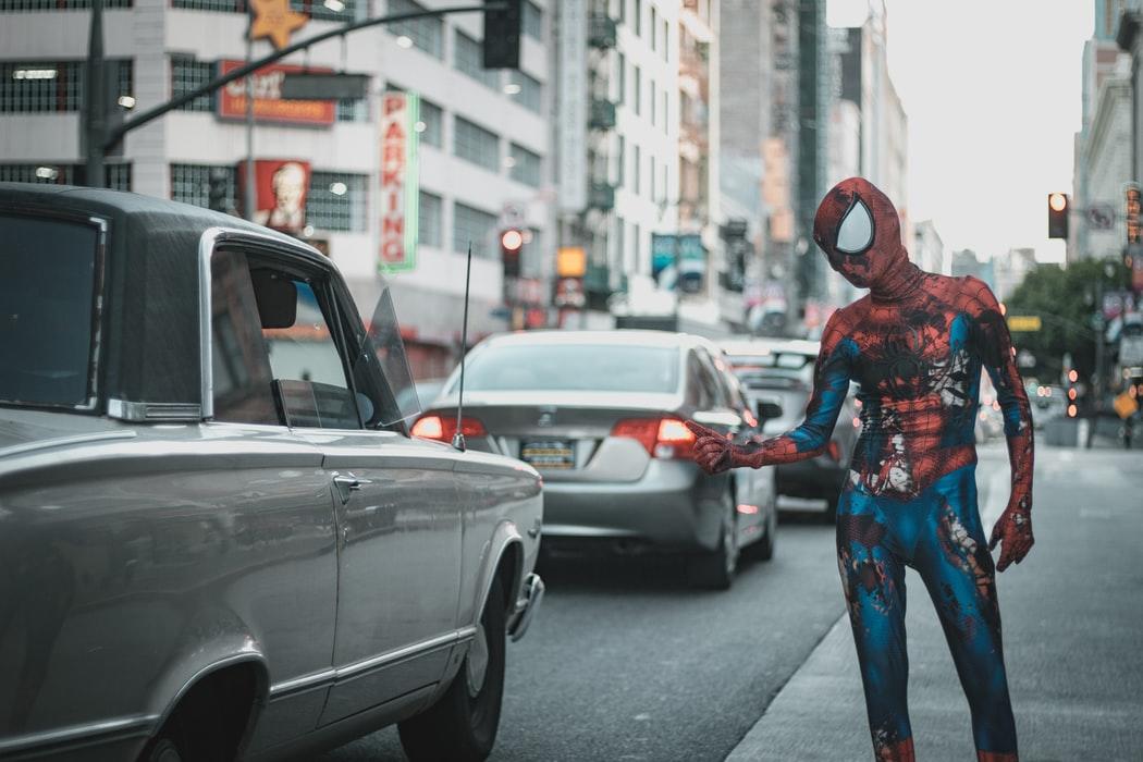 Mężczyzna przebrany za spidermana stoi na ulicy z kciukiem w górę