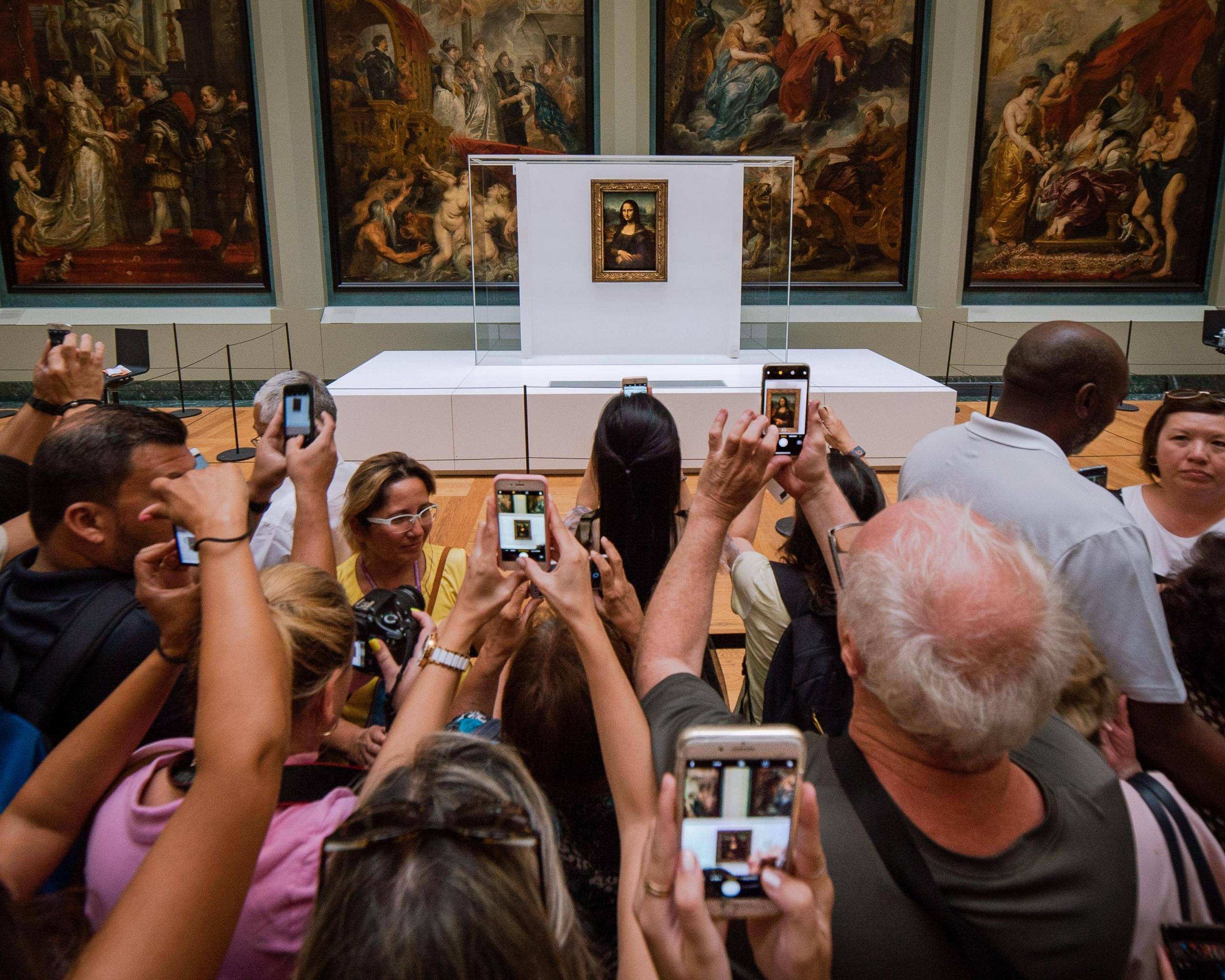 ludzie robiący zdjęcia obrazowi mona lisa w luwrze