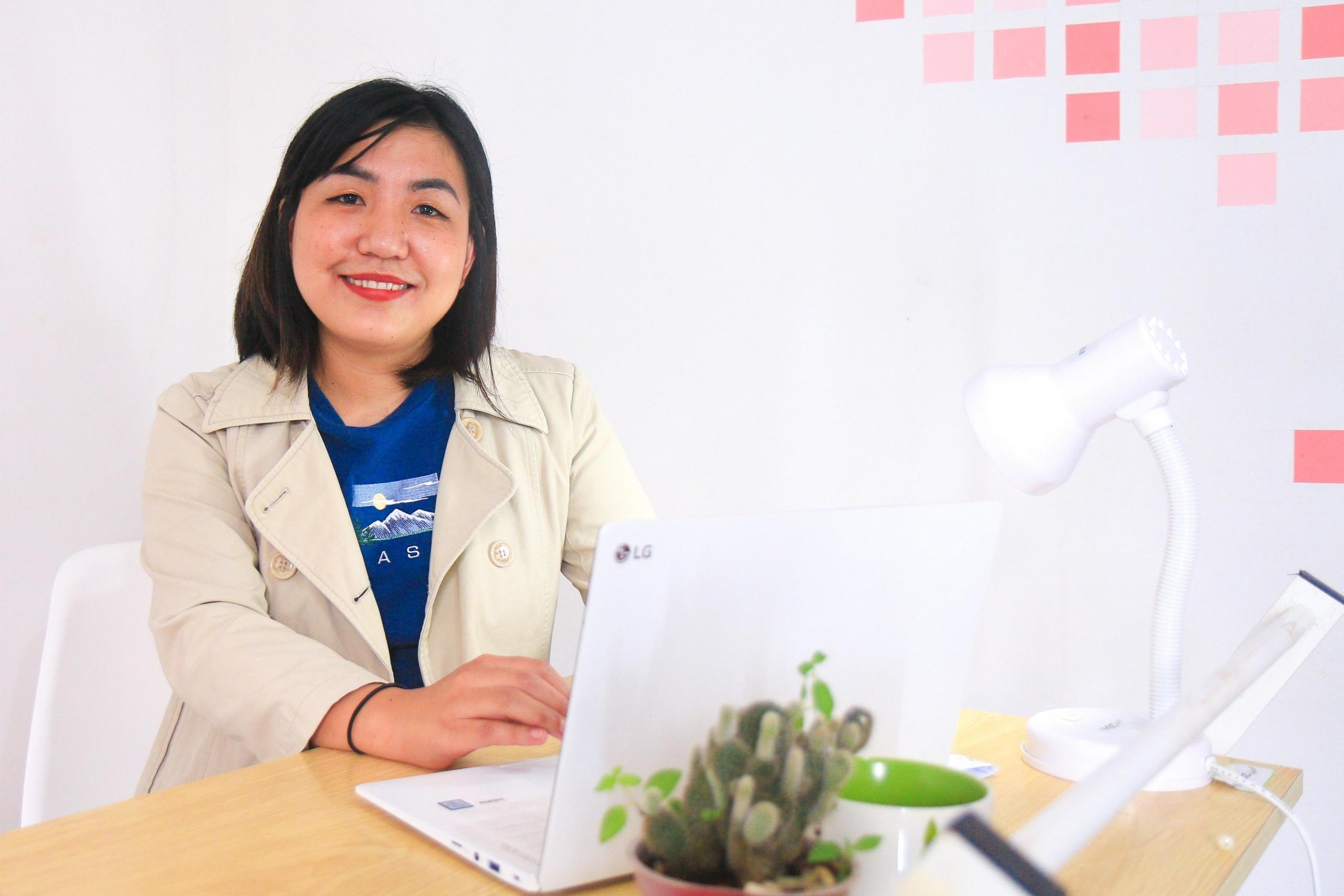 Kobieta przy biurku z komputerem, karteczki samoprzylepne na ścianie.