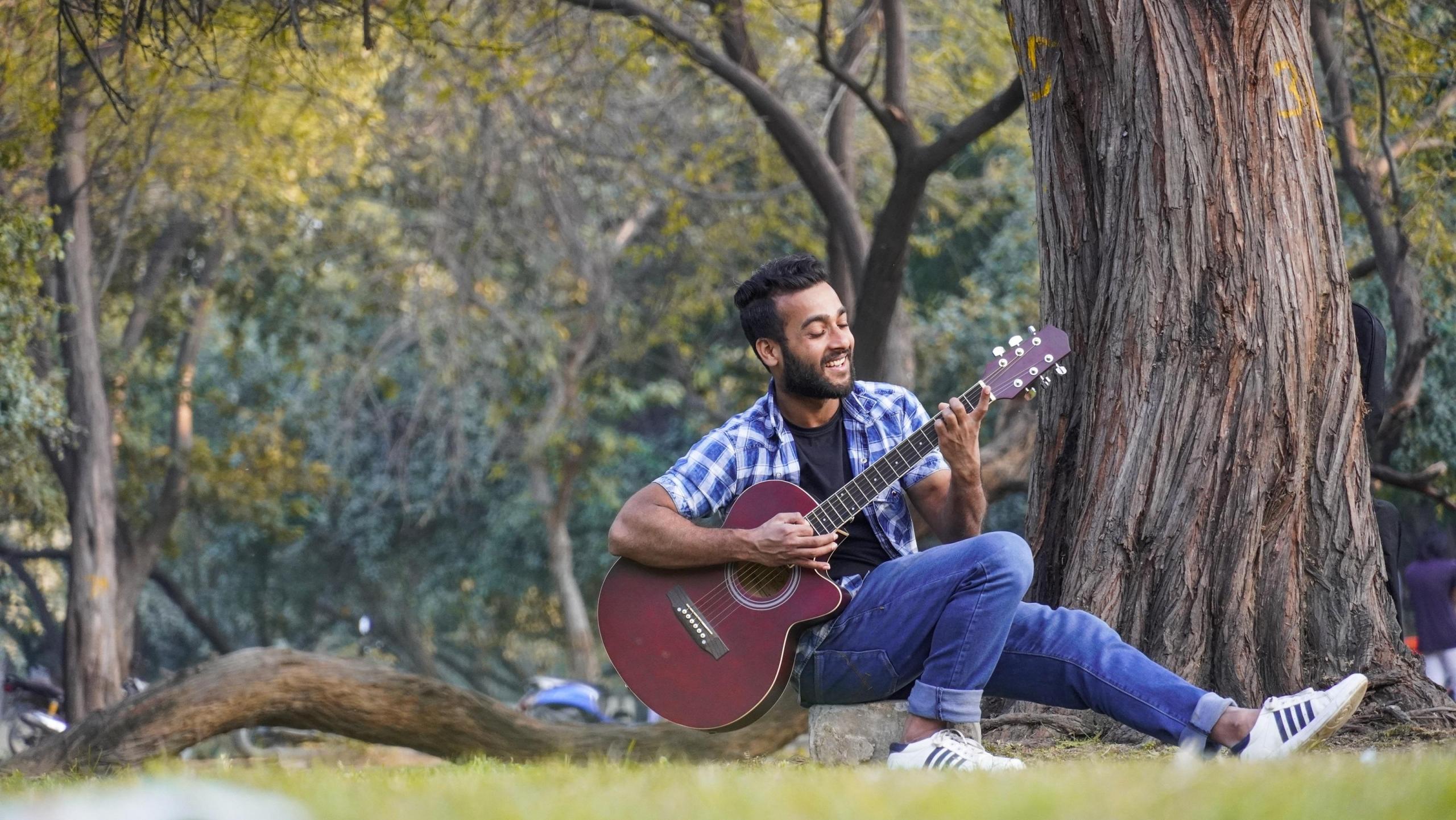 Mężczyzna z gitarą w parku.