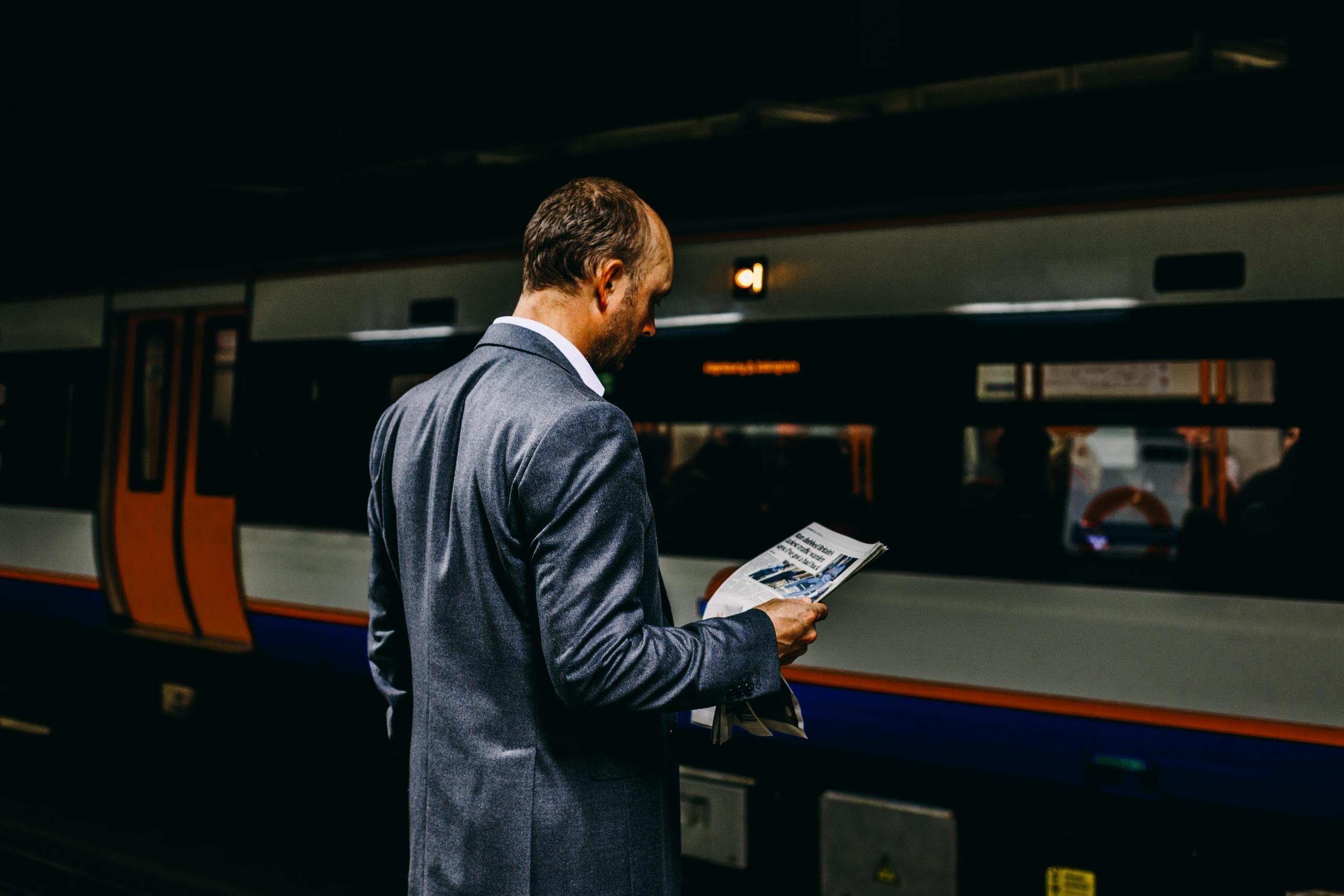 mężczyzna czytający gazetę czekając na metro