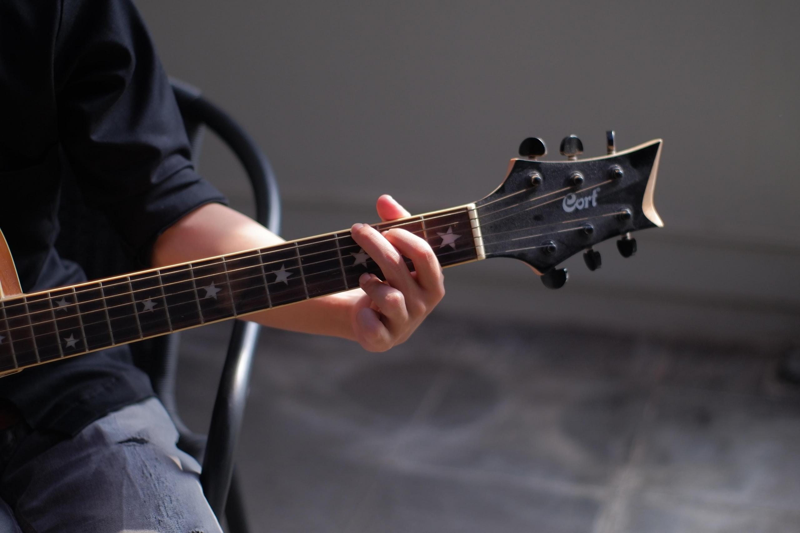Człowiek grający seksowne piosenki na gitarę, główka gitary, krzesło.