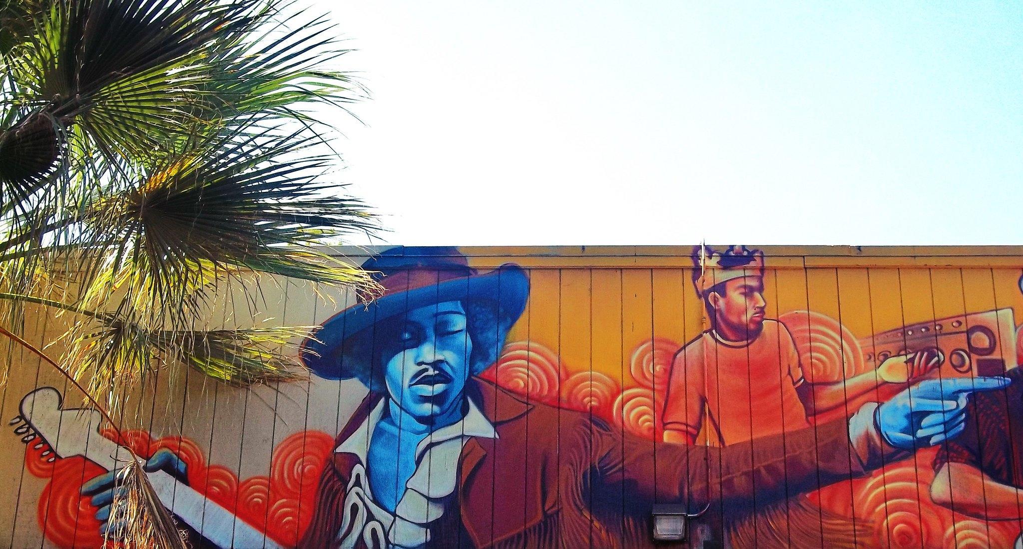 Jimmy Hendrix, znany gitarzysta, mural na płocie, drzewo.