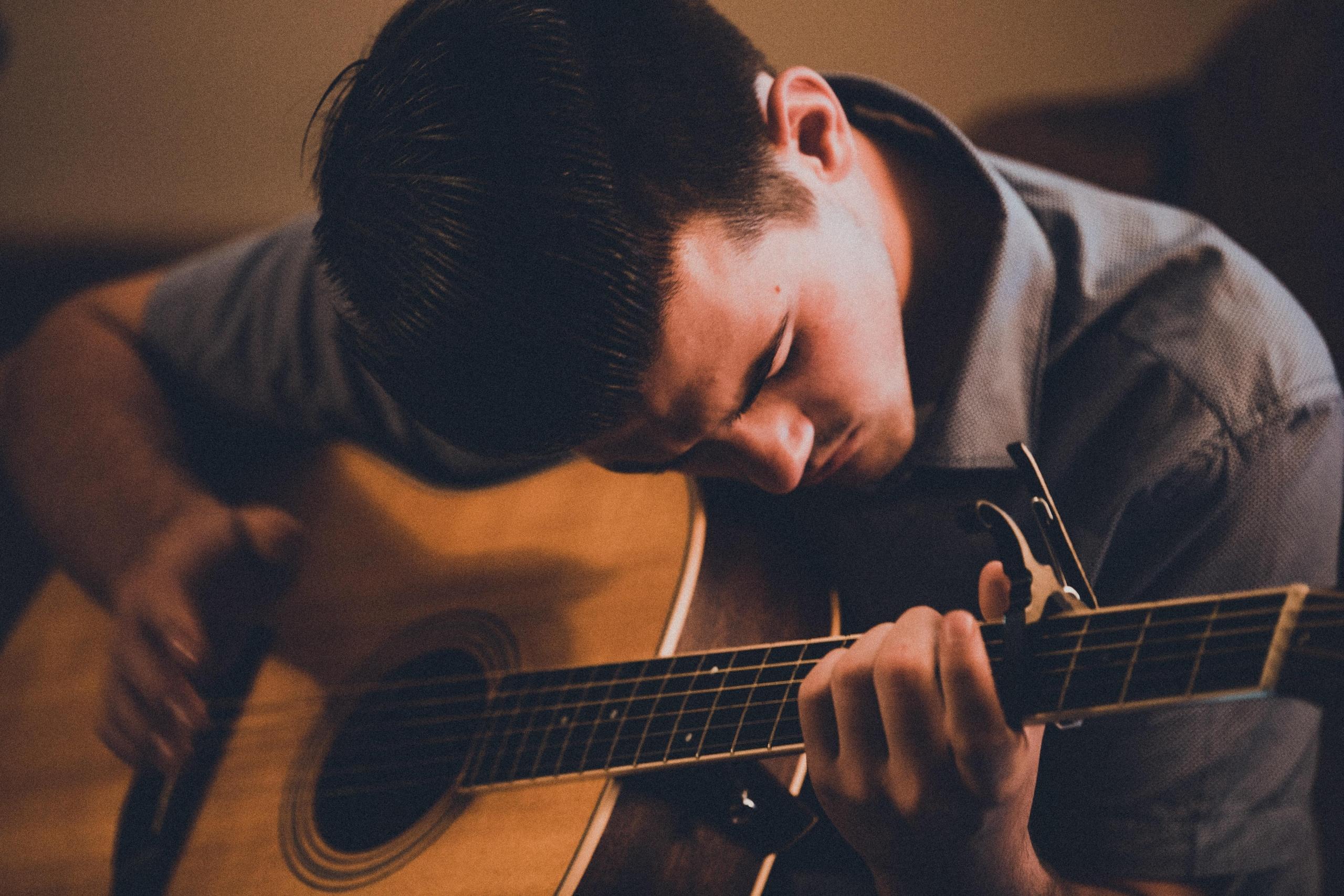 Mężczyzna korzystający z zalet gry na gitarze.