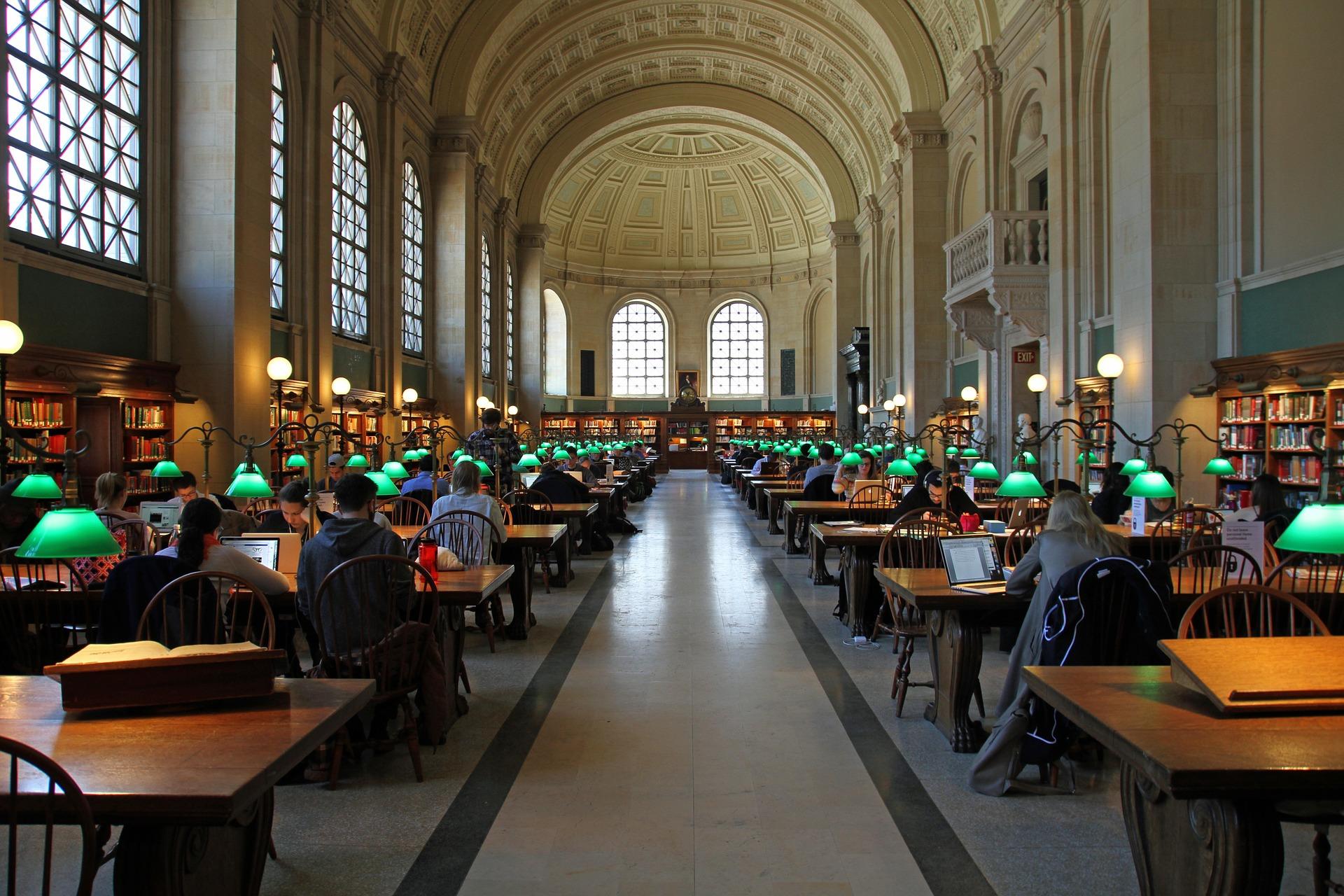 studenci przy komputerach i książkach w czytelni uniwersyteckiej