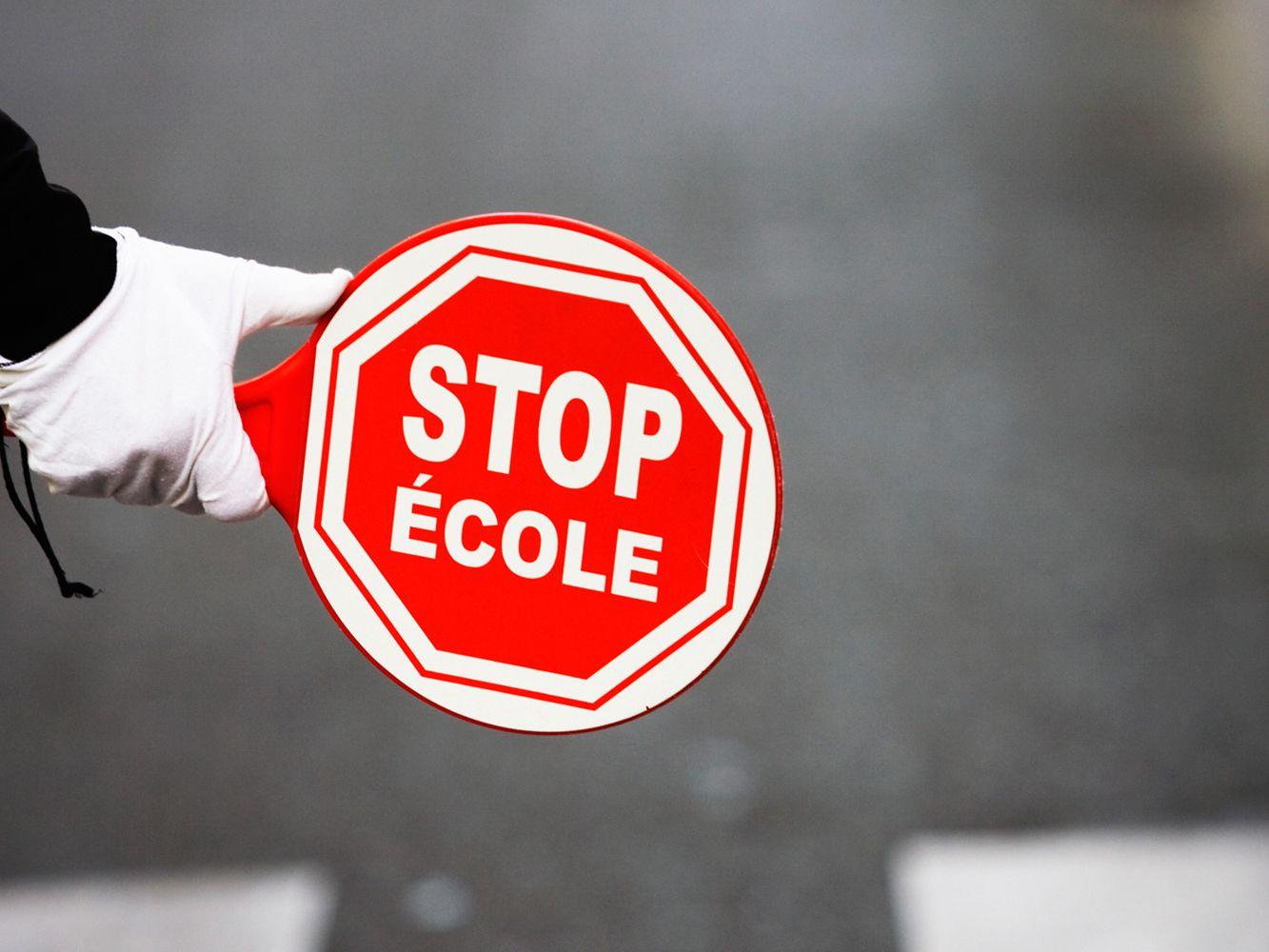 osoba w białych rękawiczkach trzymająca znak z napisem stop szkoła po francusku