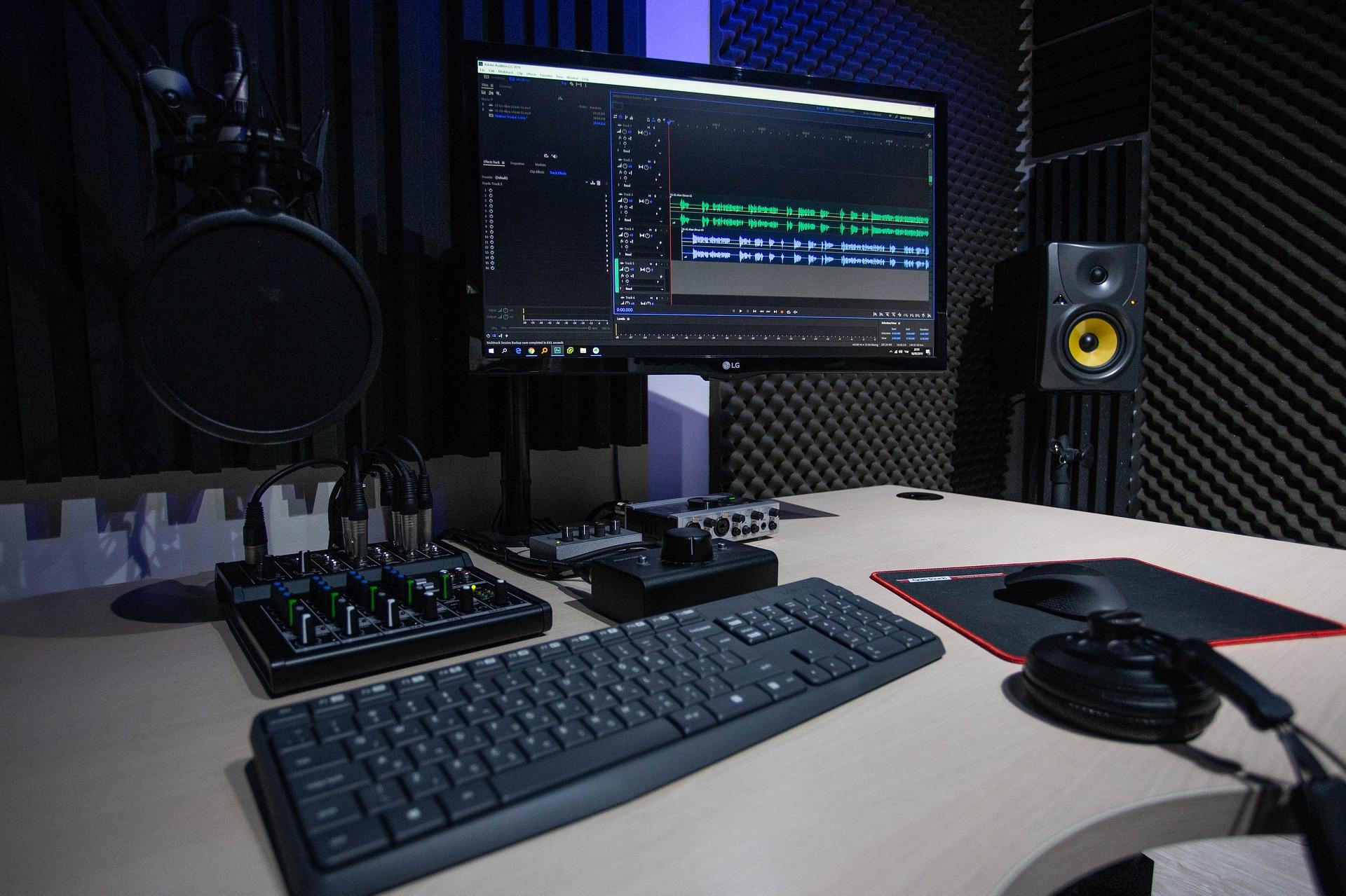 wygłuszone pomieszczenie z biurkiem komputerem oraz sprzętem do nagrywania podcastów lub muzyki