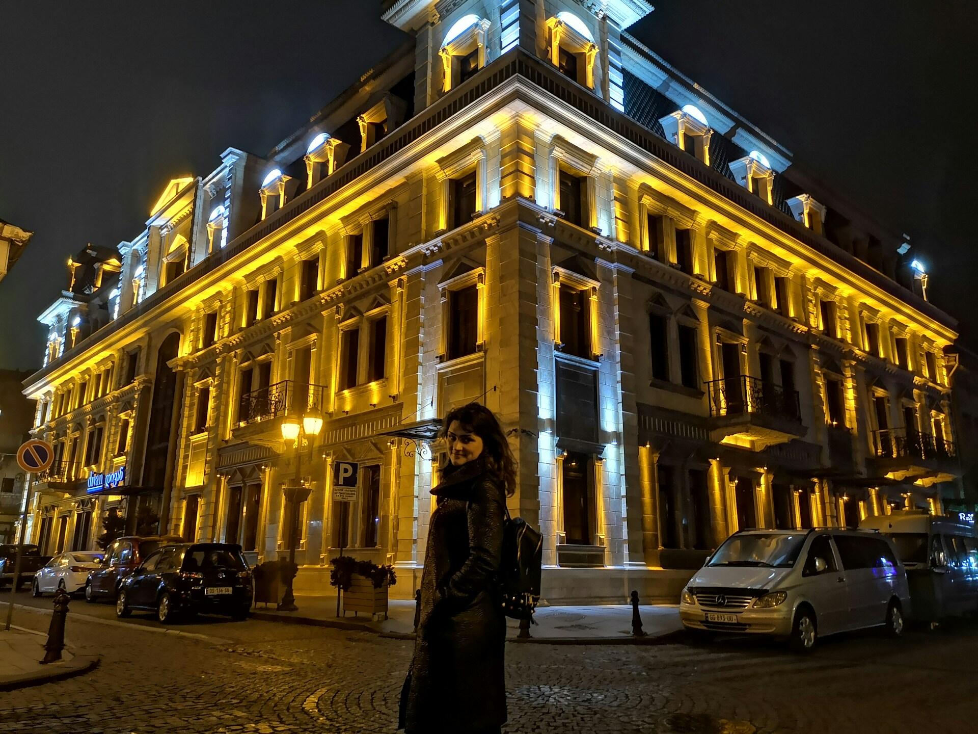 Kobieta przy oświetlonym budynku nocą.