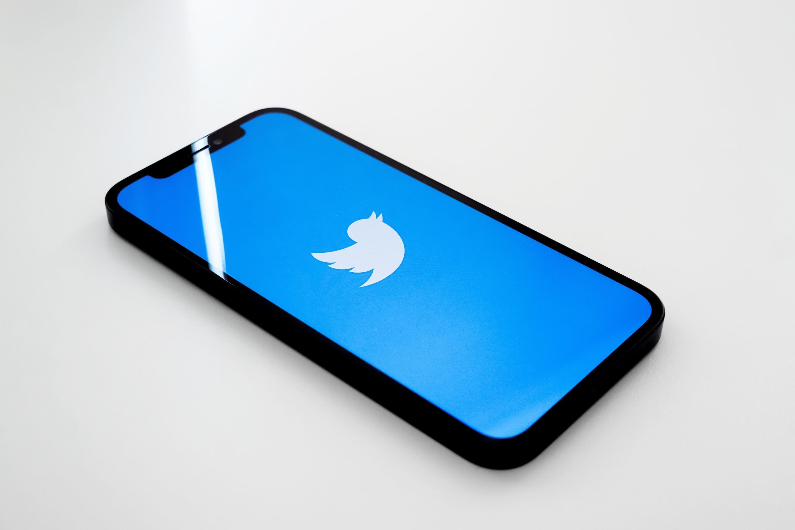 strona startowa aplikacji twitter na smartfonie leżącym na białym stole