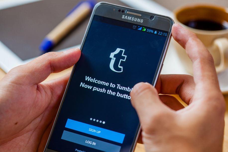 osoba trzymająca smartfon na którym wyświetlana jest strona logowania w aplikacji tumblr