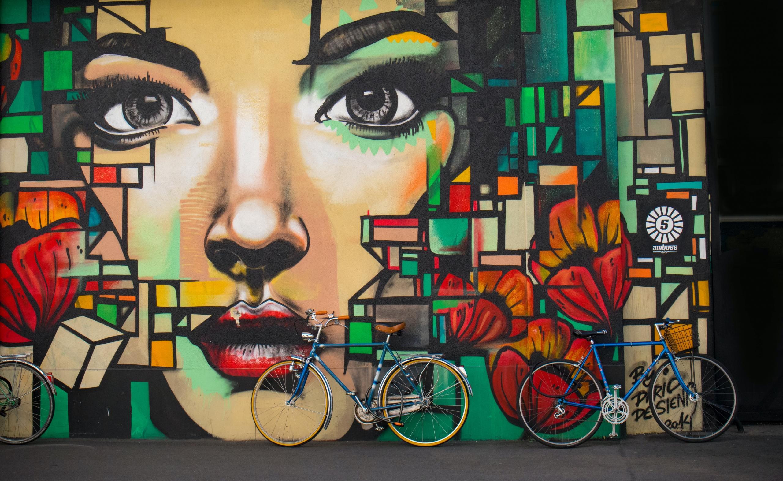 Mural, twarz kobiety, rowery, ulica.