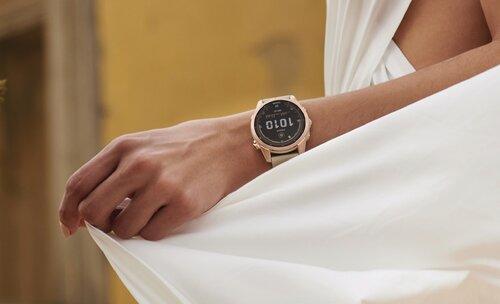 kobieca dłoń z smartwatchem na nadgarstku trzymająca biały materiał ubrania