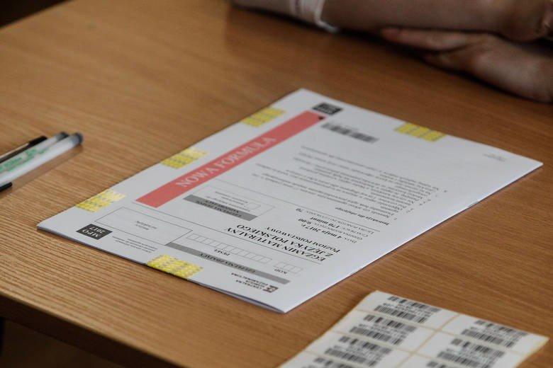 arkusz maturalny z języka polskiego leżący na ławce obok leżą naklejki i długopis