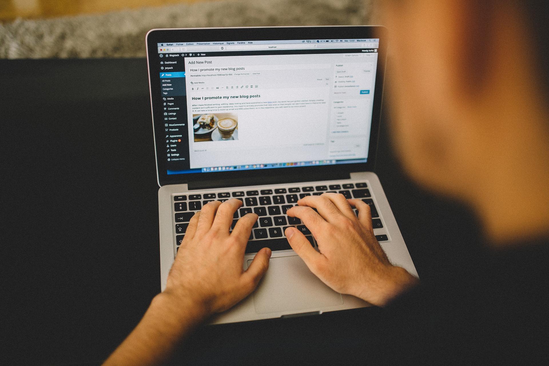 mężczyzna pracujący w wordpressie na laptopie trzymany na kolanach