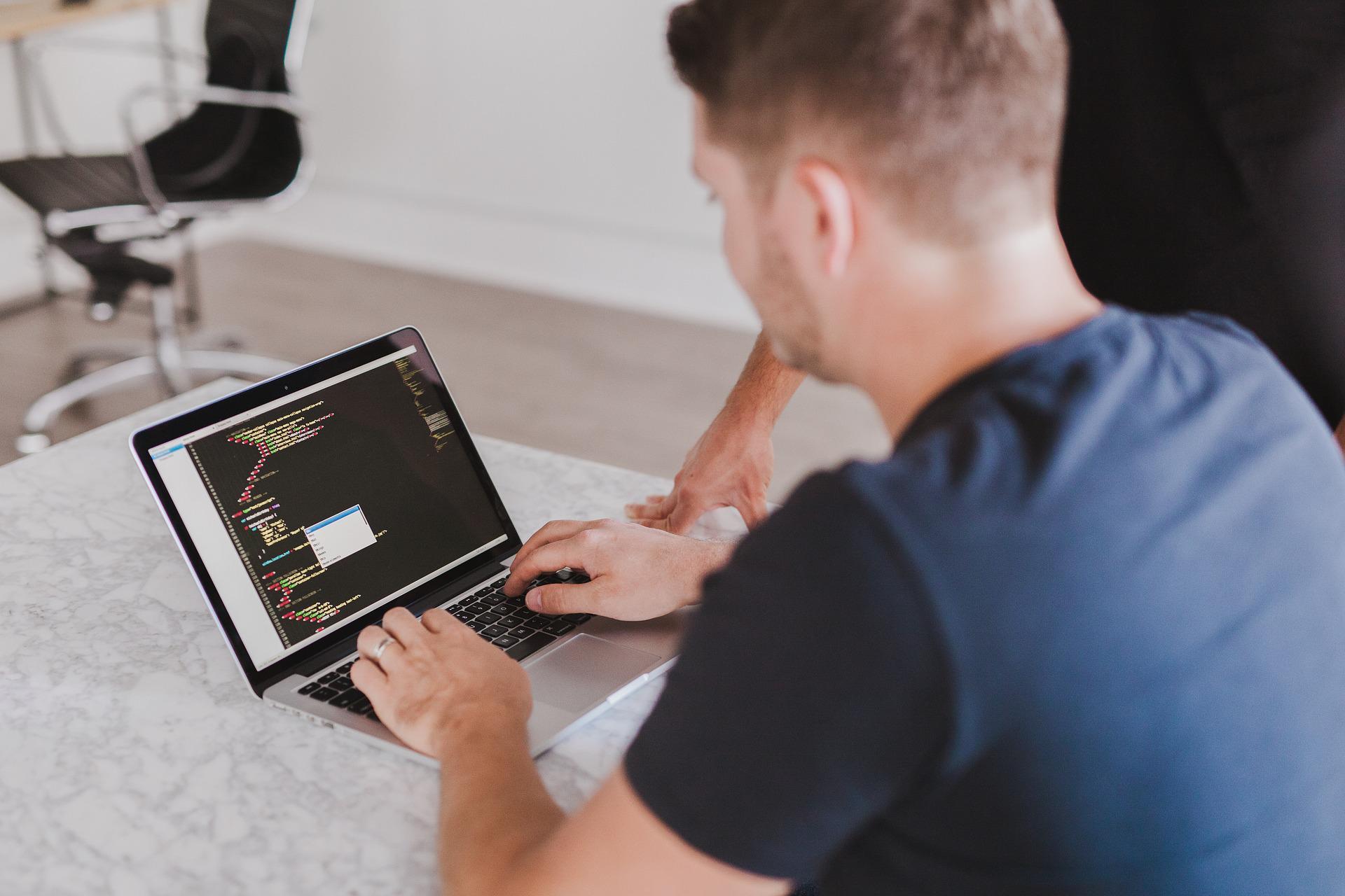 mężczyzna piszący na laptopie kod w html