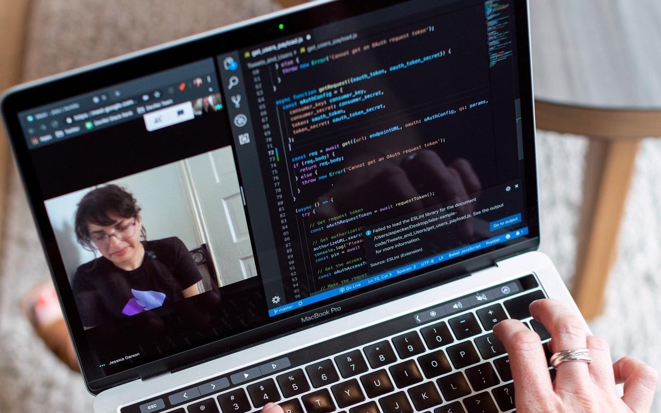 osoba pisząca kod i biorąca udział w videokonferencji