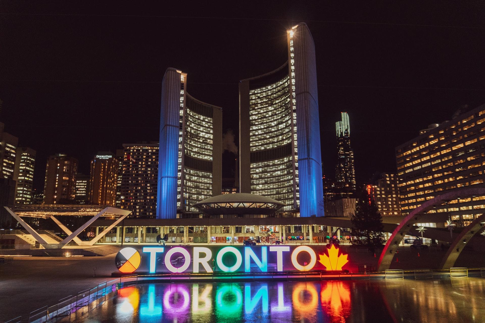 wielki neon z napisem toronto na tle wysokich i oświetlonych budynków widzianych w nocy