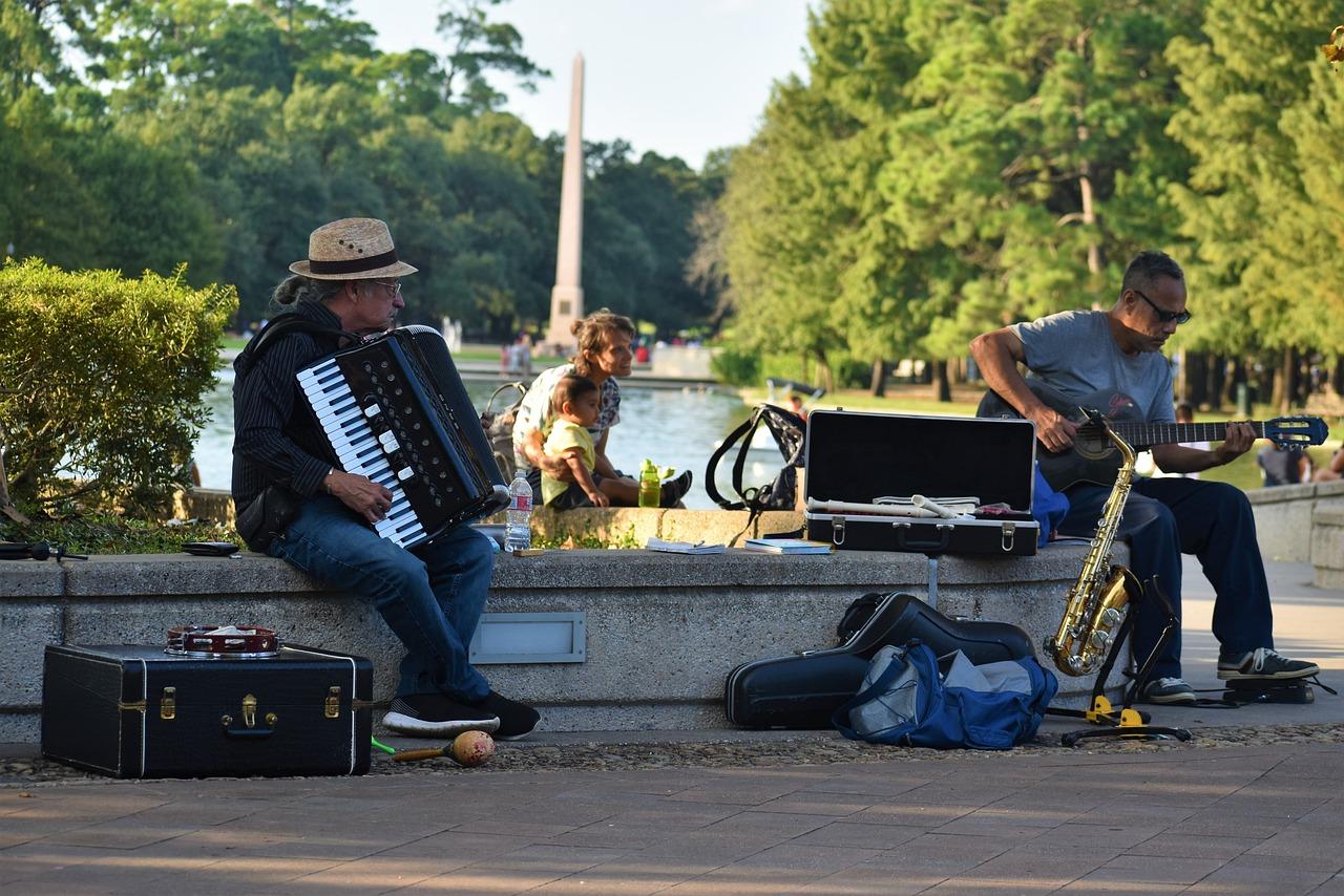 uliczni muzycy gitara akordeon drzewa zarośla murek chodnik saksofon flet tamburyn