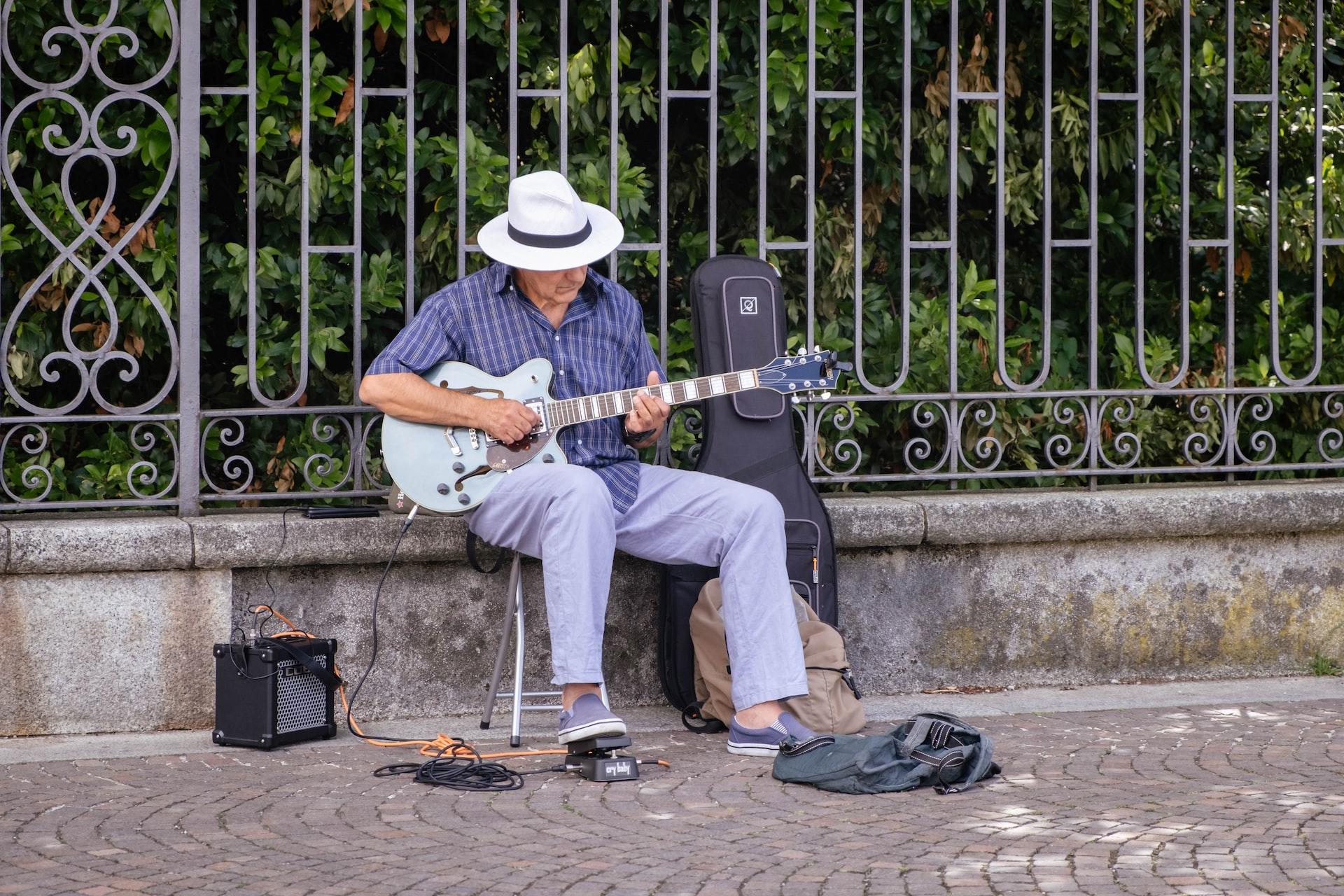 płot beton biały kapelusz biała gitara siedzący mężczyzna
