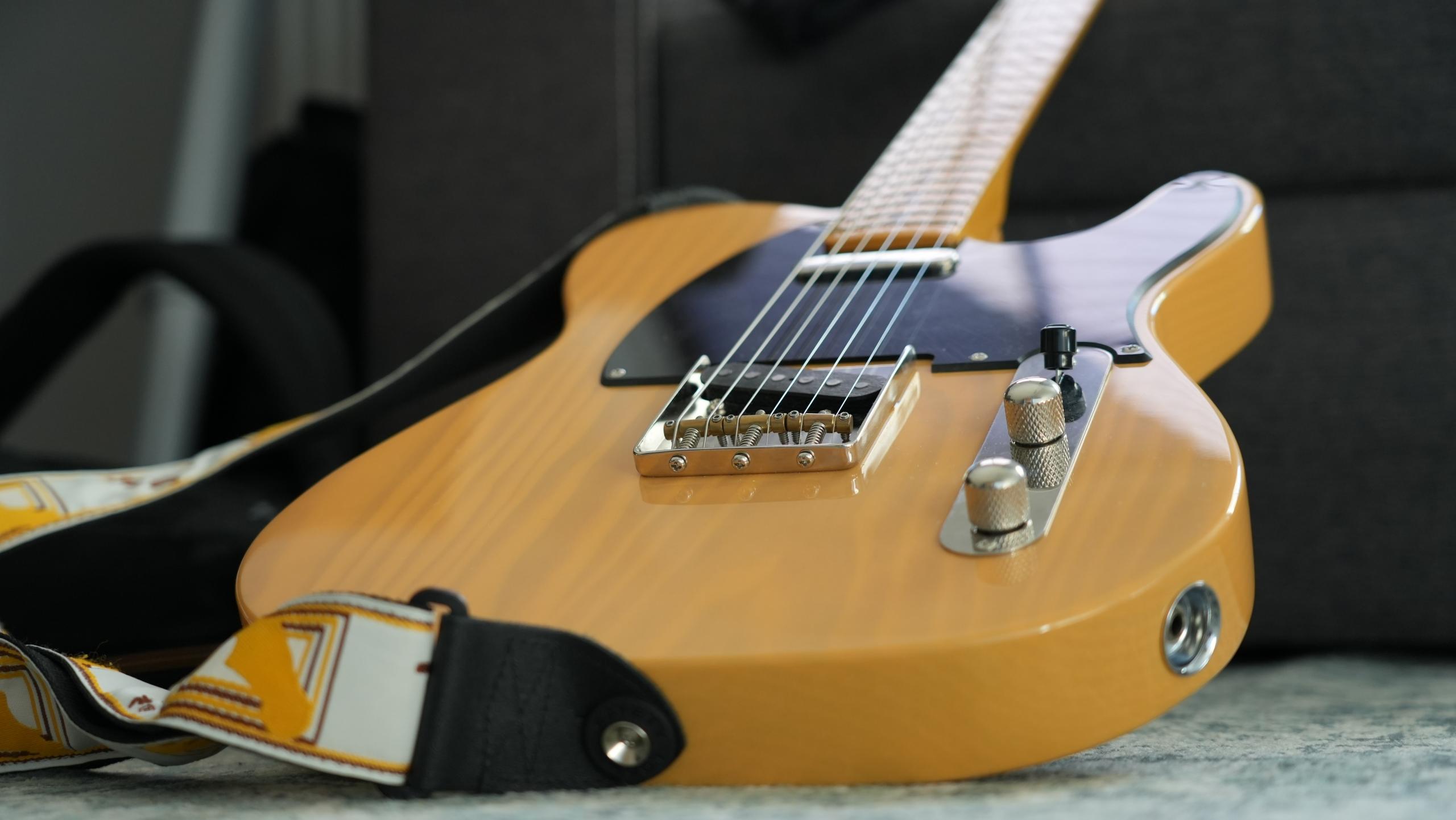 beżowa drewniana gitara na podłodze