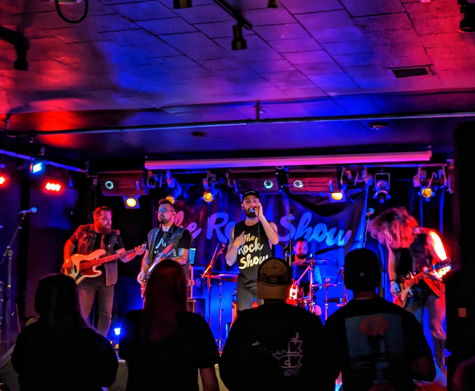 Grupa muzyków na ciemnej scenie, oświetlonej na niebiesko.