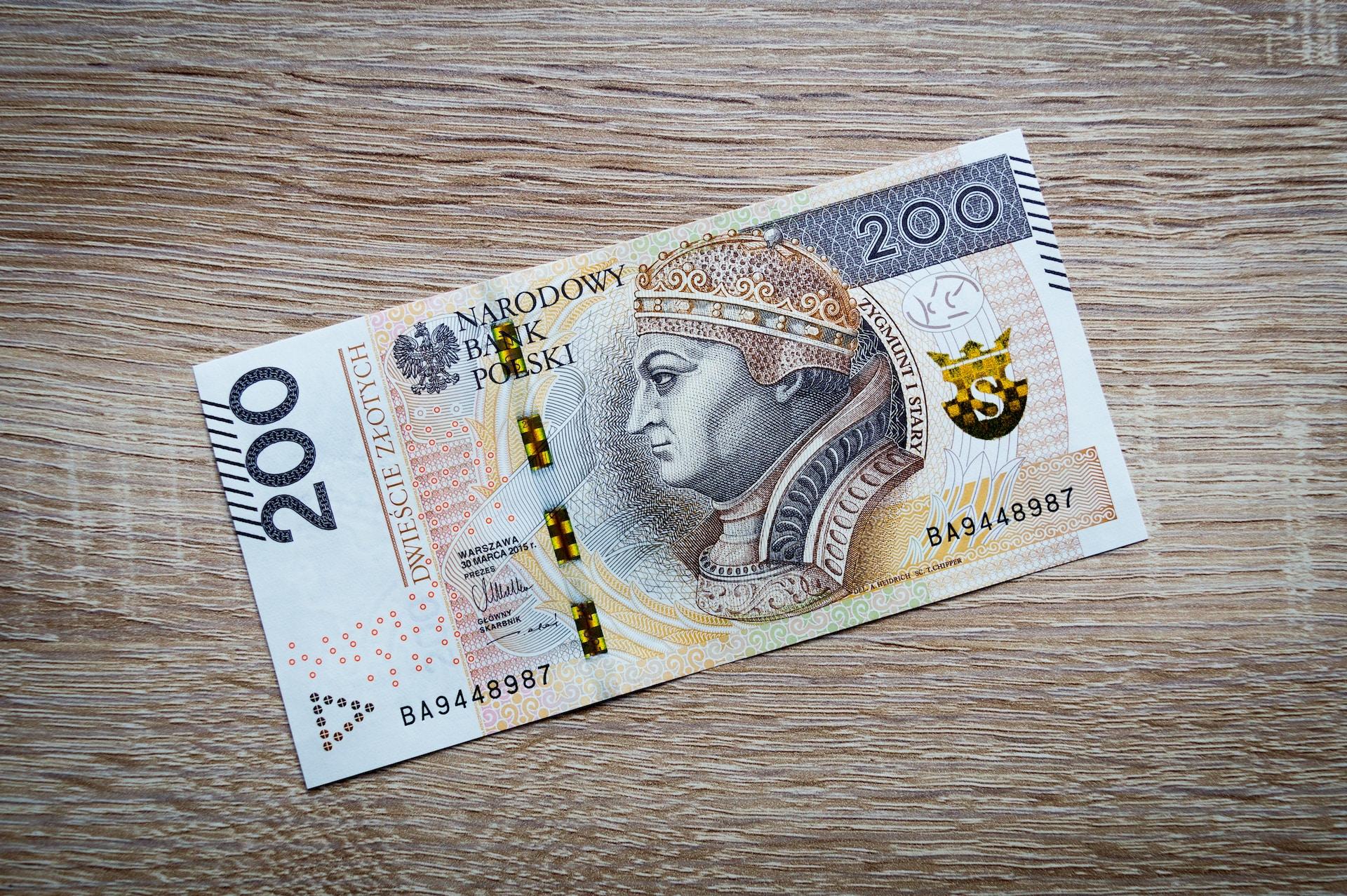 Banknot 200 złotych na drewnianej powierzchni.