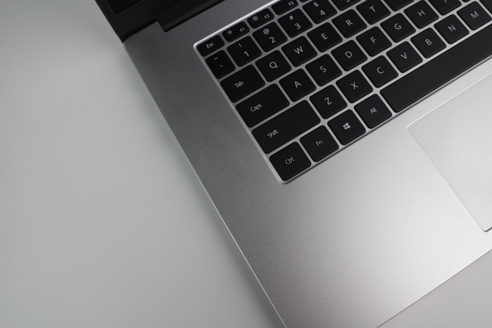 Otwarty srebrny laptop z czarną klawiaturą.