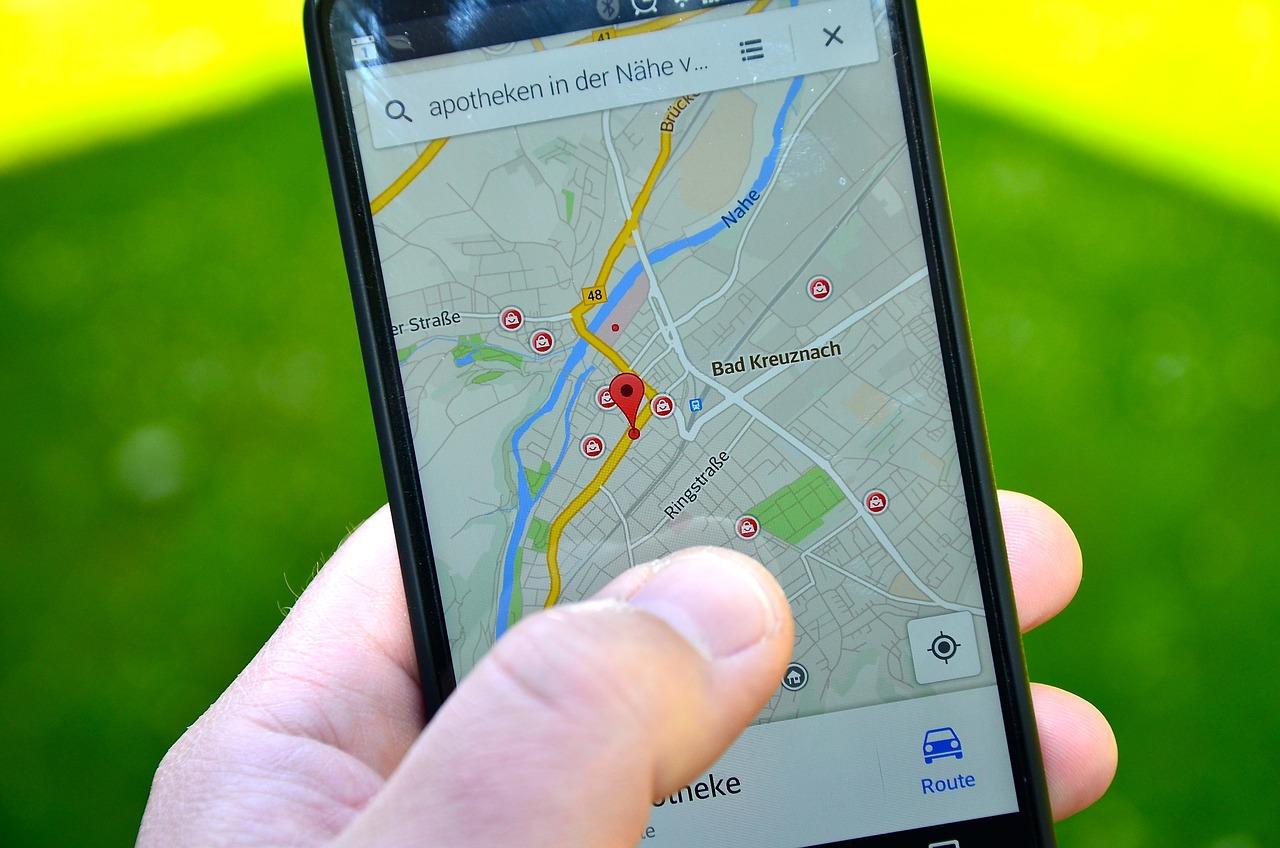 Telefon z mapą, w ręku, nad trawą.