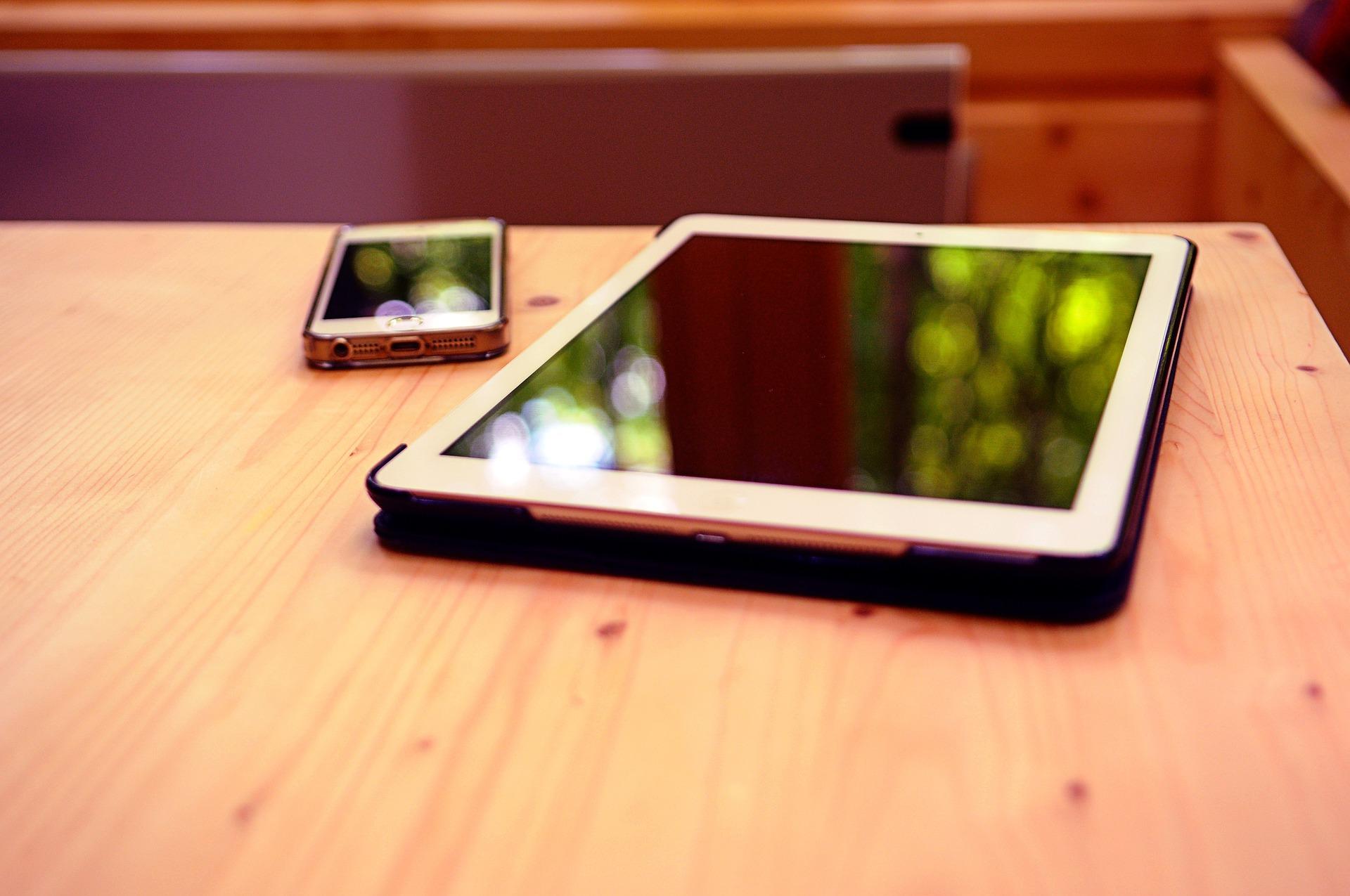 Tablet, telefon, stół drewniany.