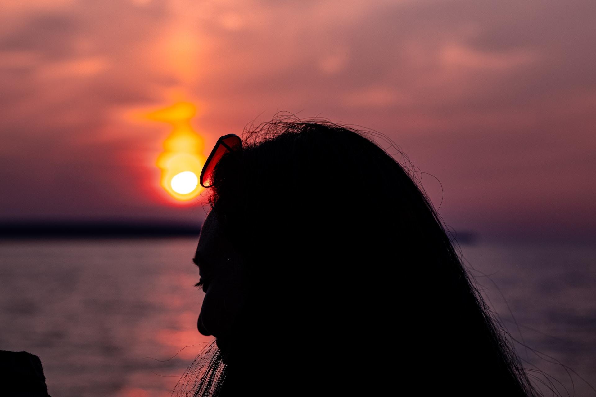 Zachód słońca nad wodą, głowa kobiety.