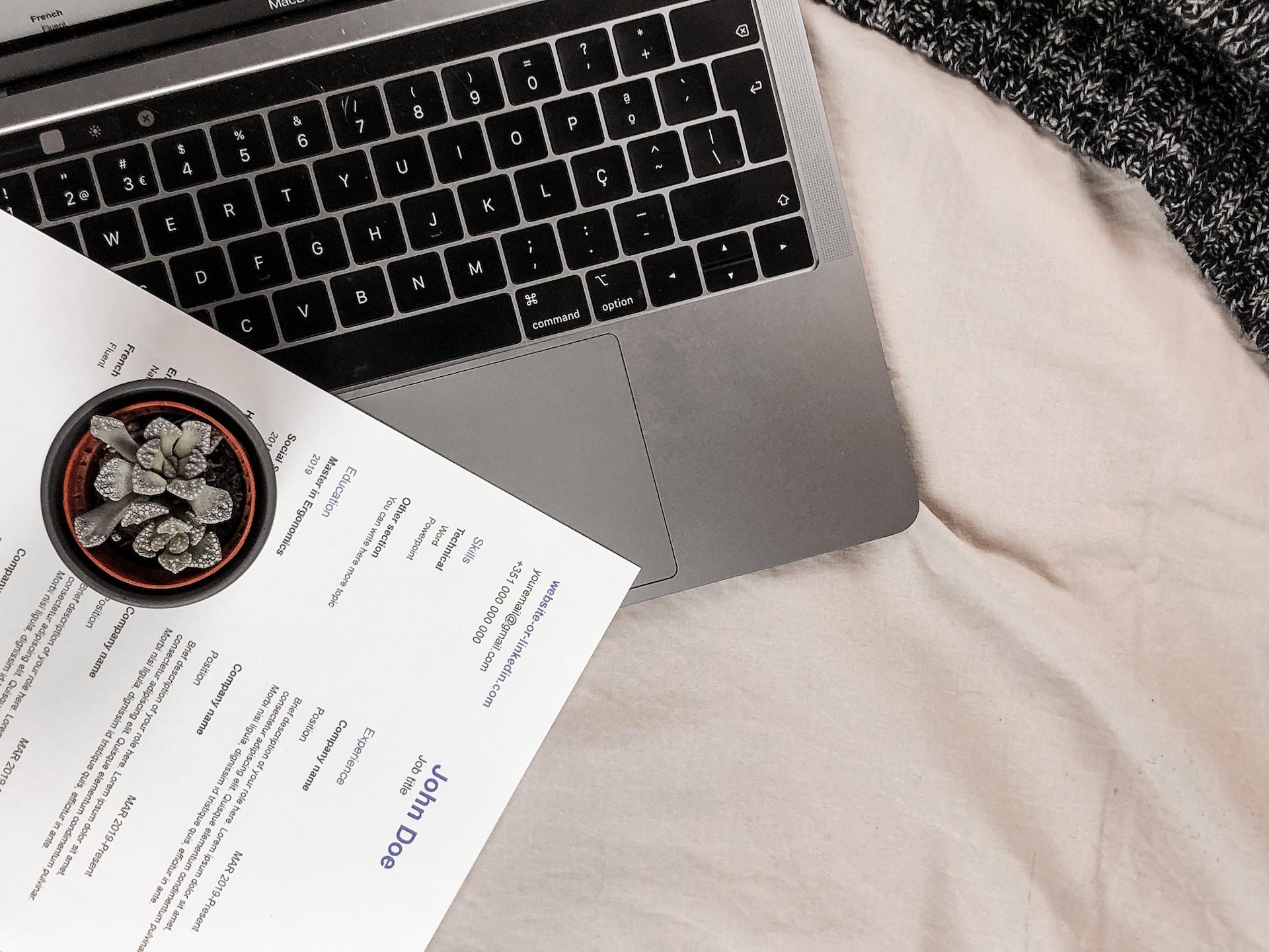 Laptop na białej pościeli, curriculum vitae, cv.