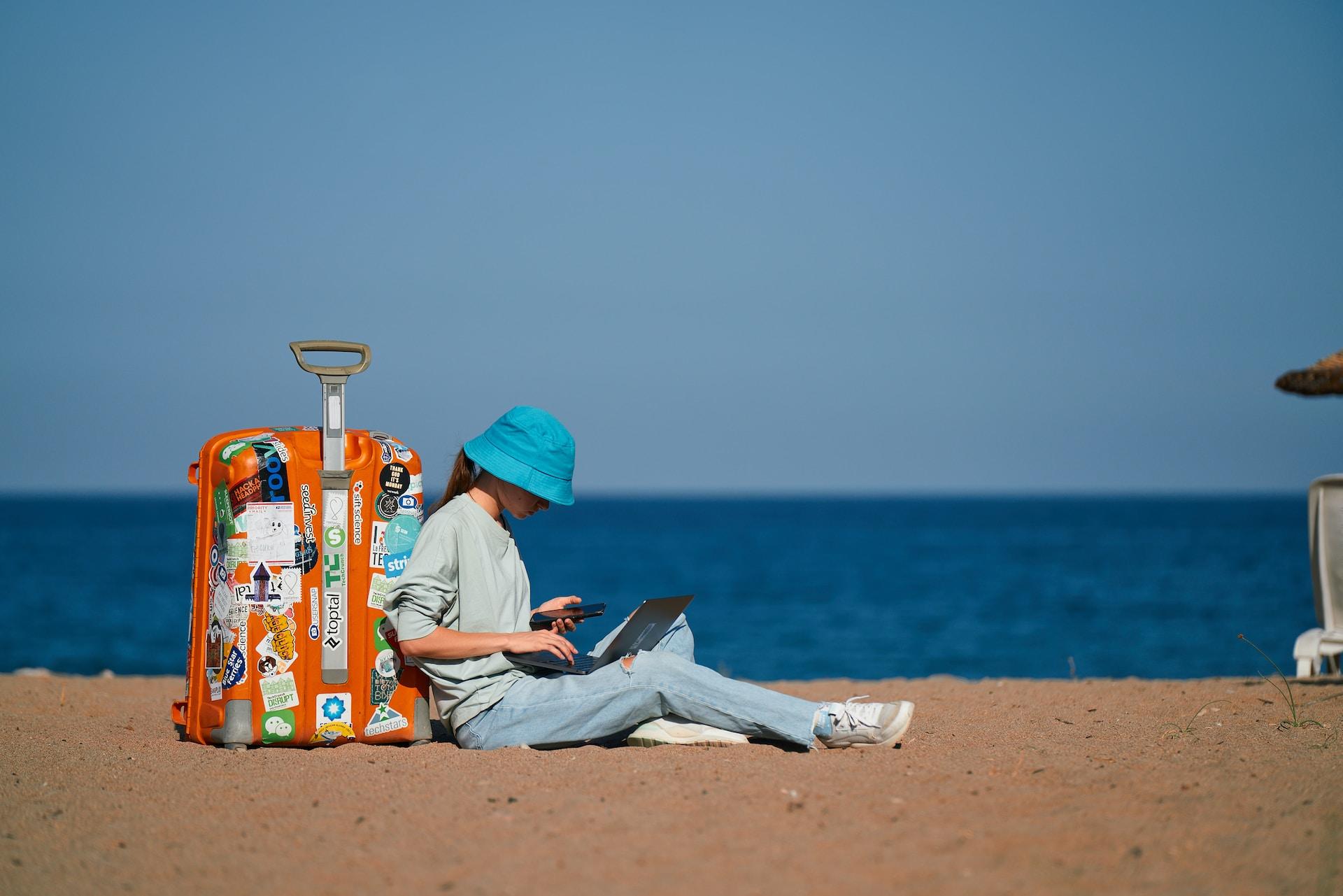 Kobieta na plaży, walizka, piasek, morze, niebo.