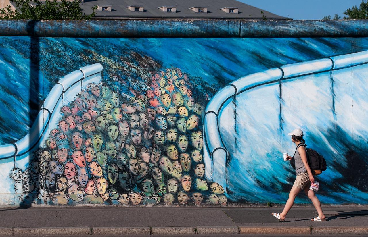 Mural, mur berliński, kobieta, tłum ludzi.