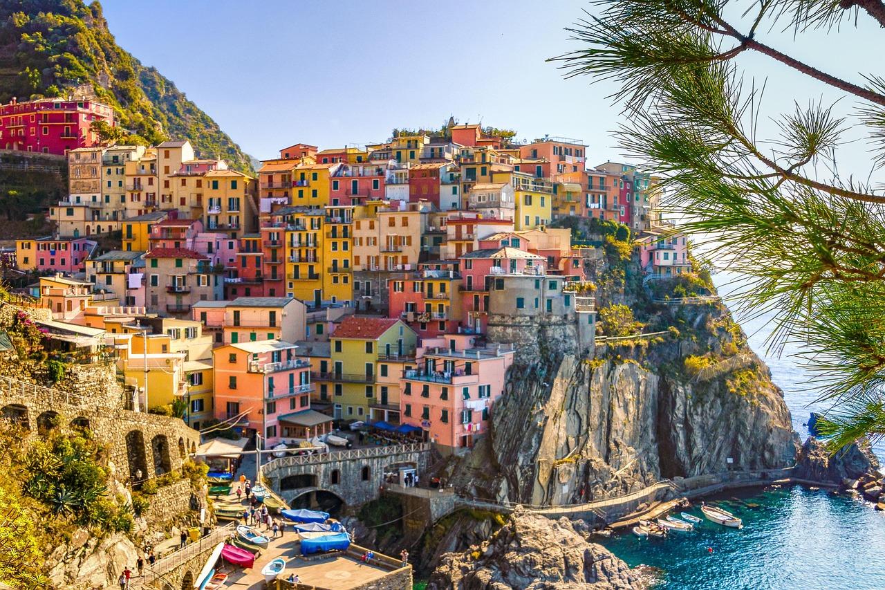 Cinque terre, kolorowe domki na stromym wybrzeżu, niebieska woda, kamieniste wybrzeże