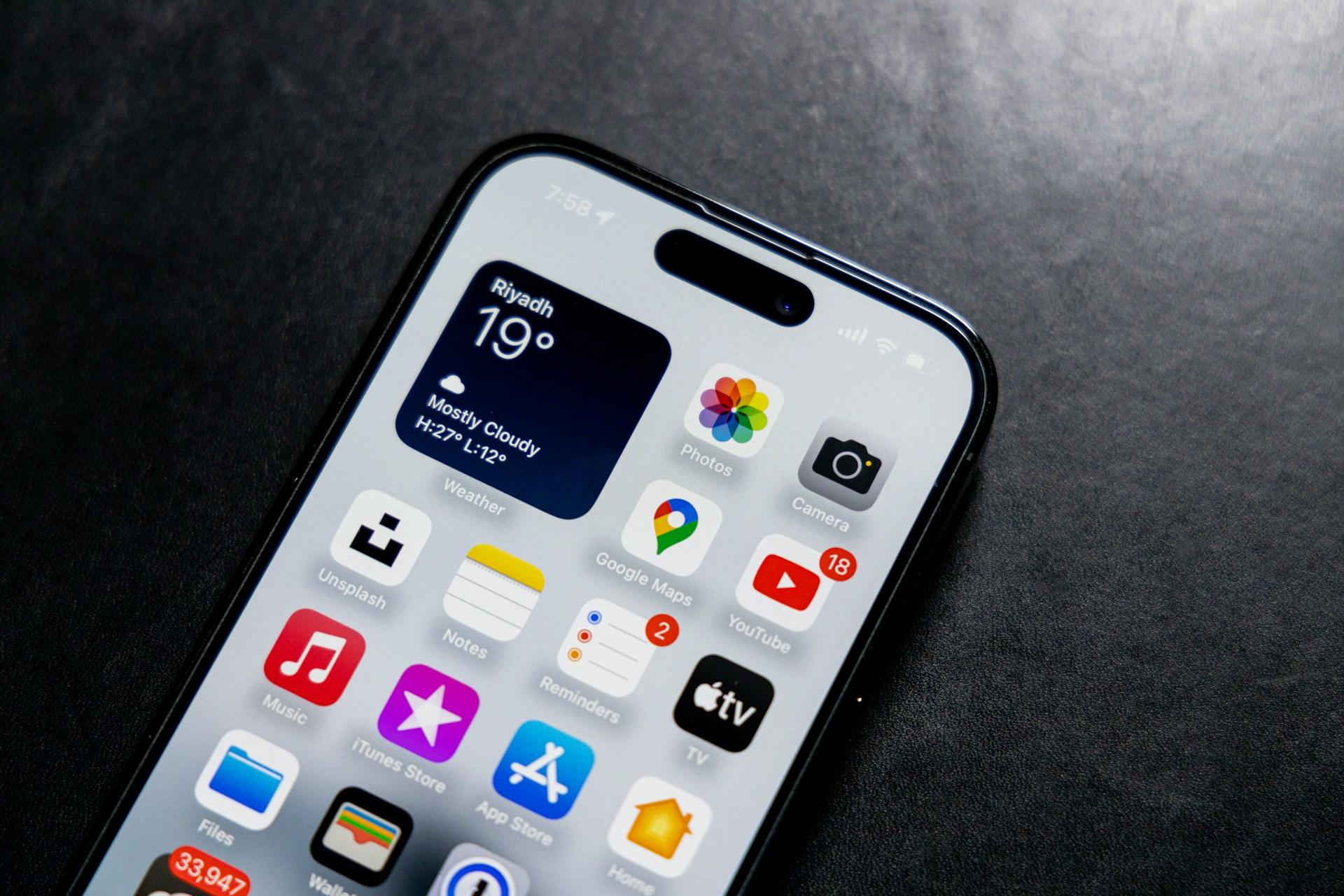 Telefon na czarnym stole, ikony aplikacji mobilnych, aplikacje na telefonie.