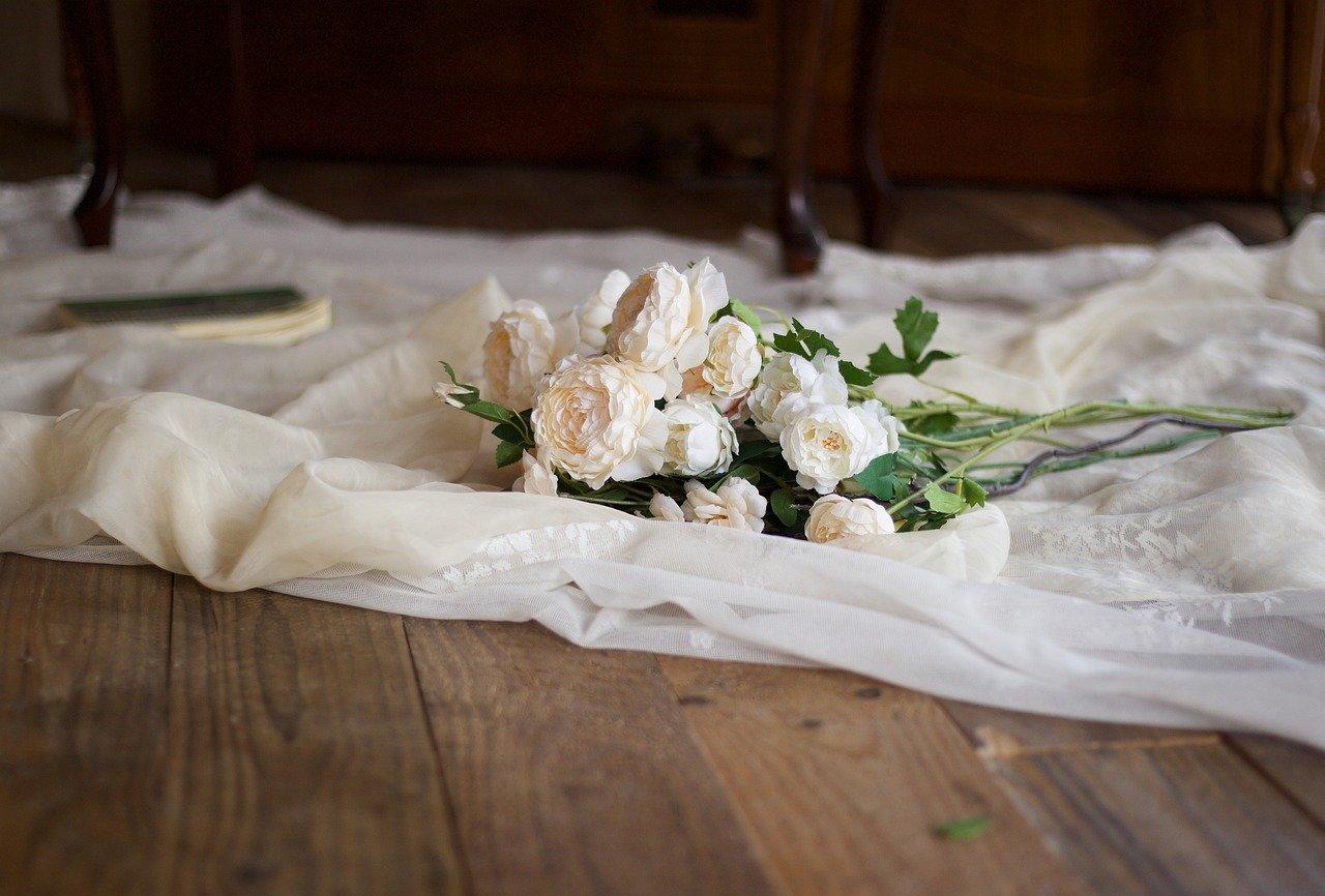 Biały materiał na drewnianej podłodze, białe kwiaty, martwa natura.