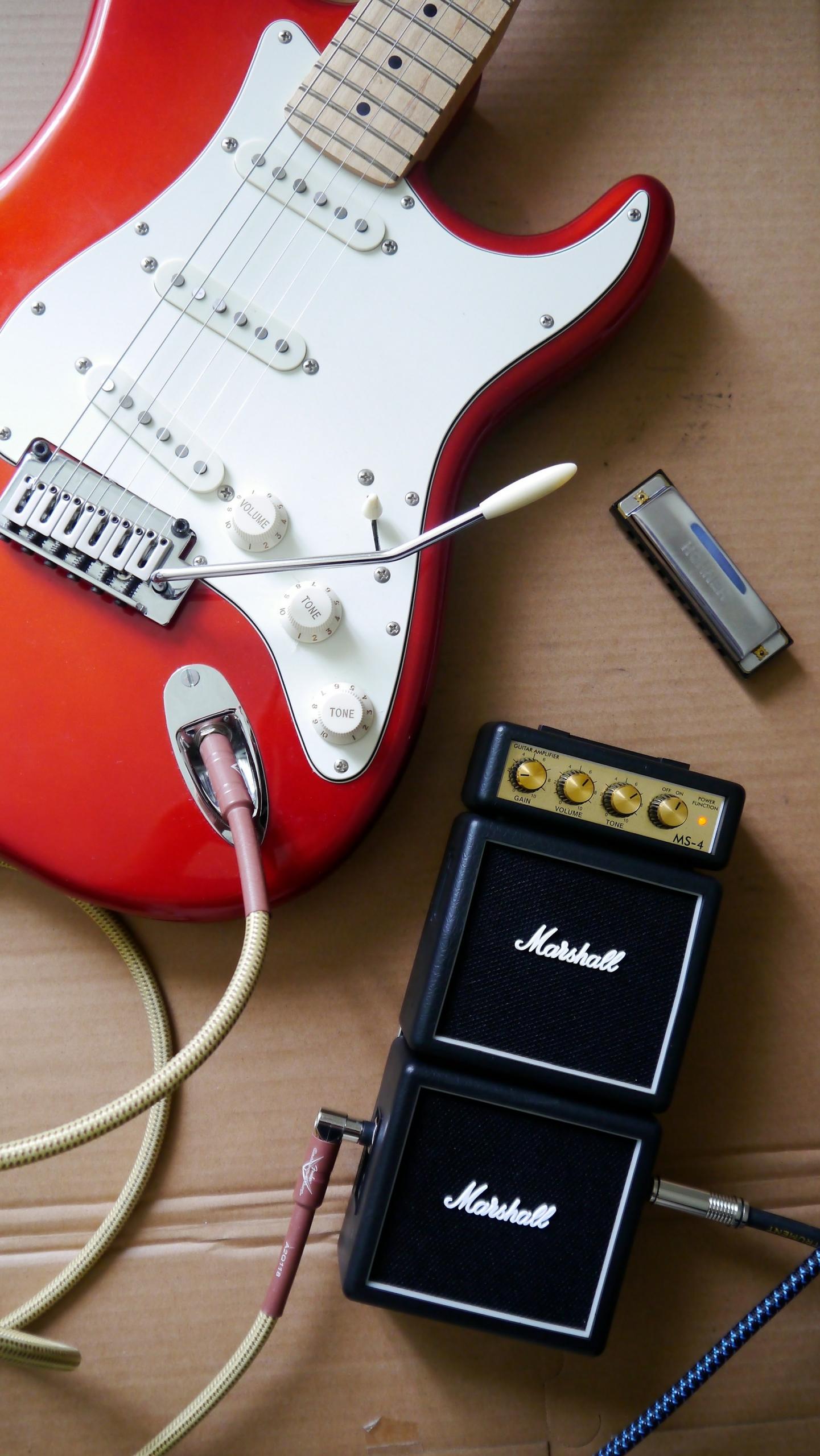 Czerwono-biała gitara elektryczna, wzmacniacz do gitary, harmonijka.