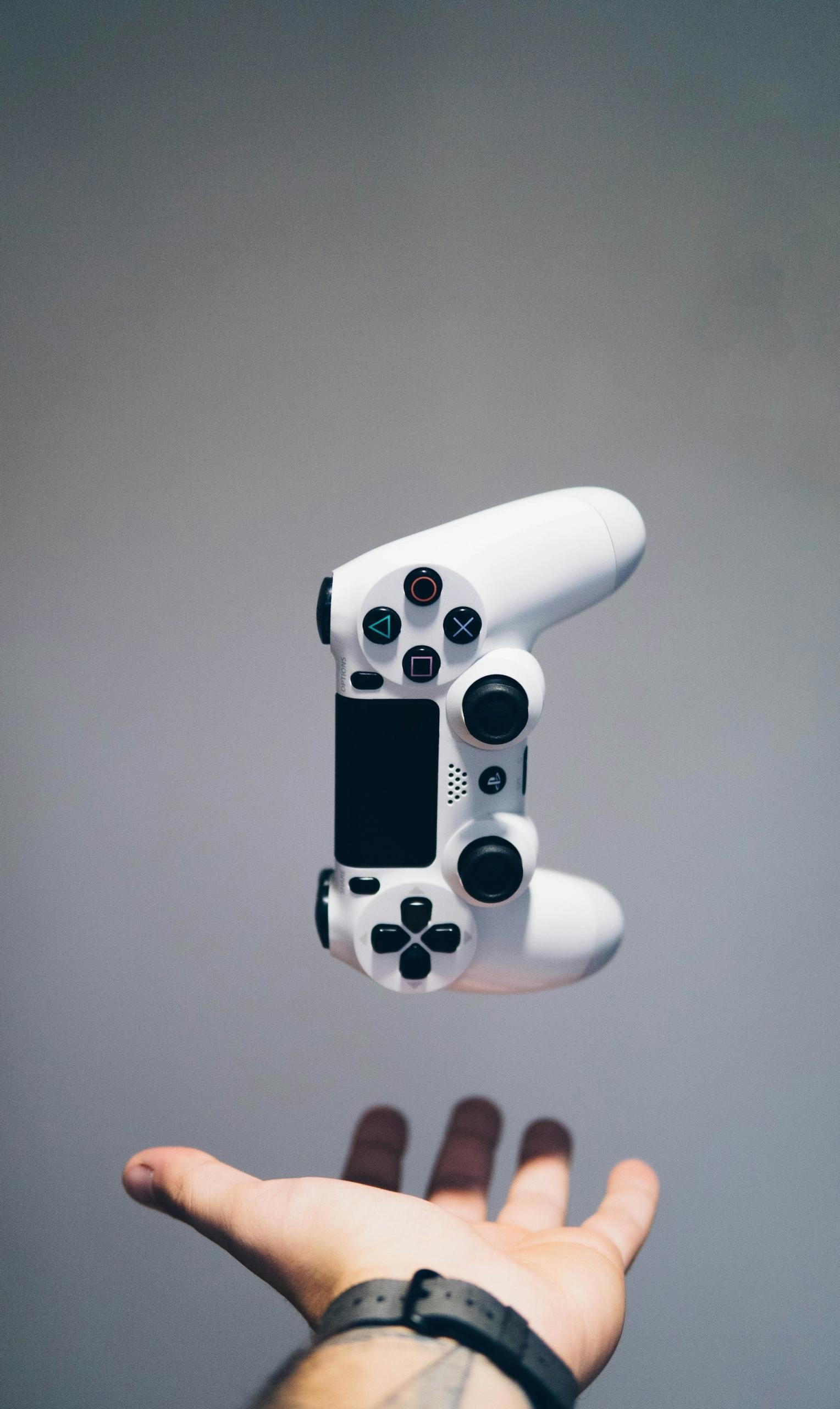 Biały kontroler Sony PlayStation nad otwartą dłonią.