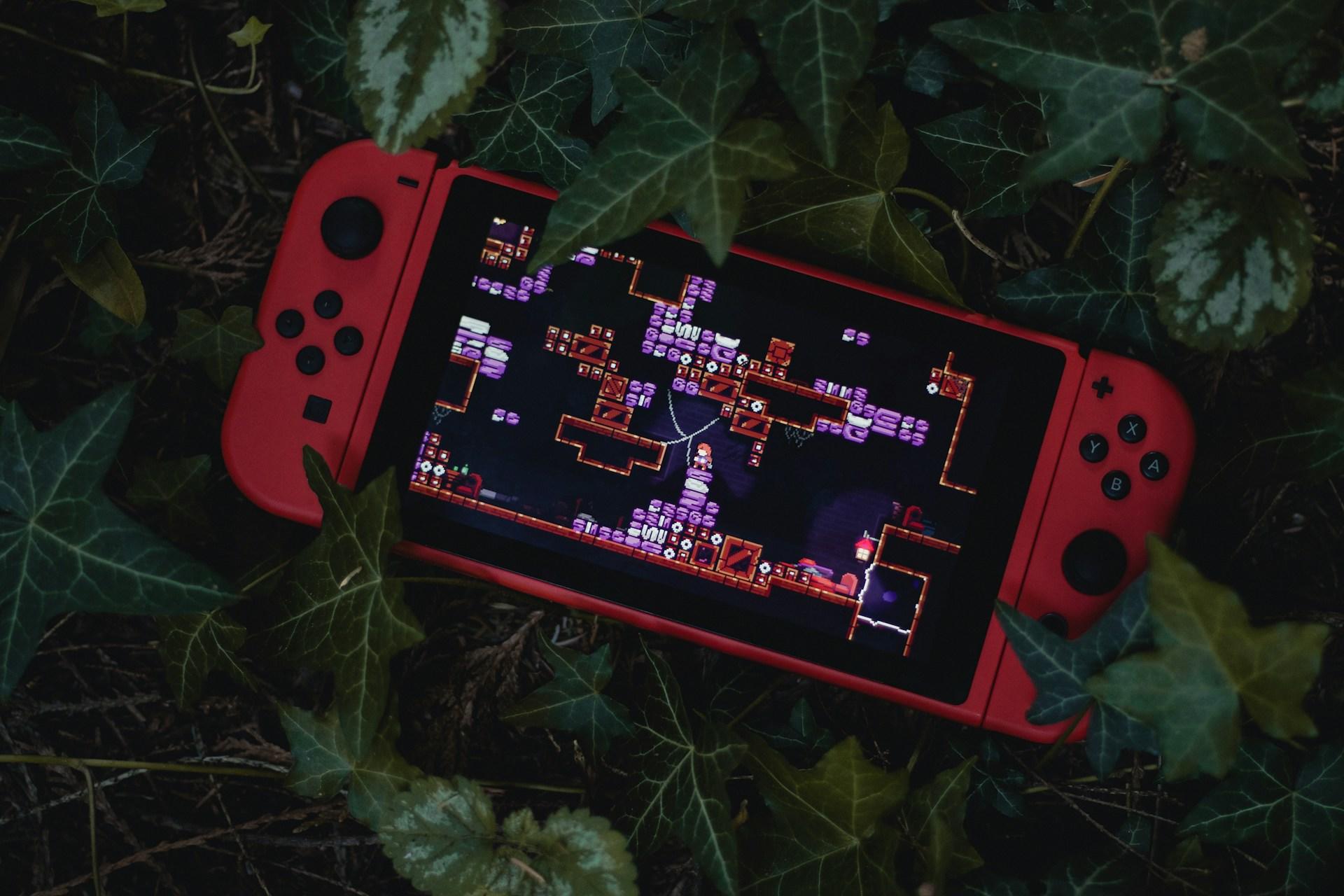 Czerwony Switch leżący na zielonym bluszczu.