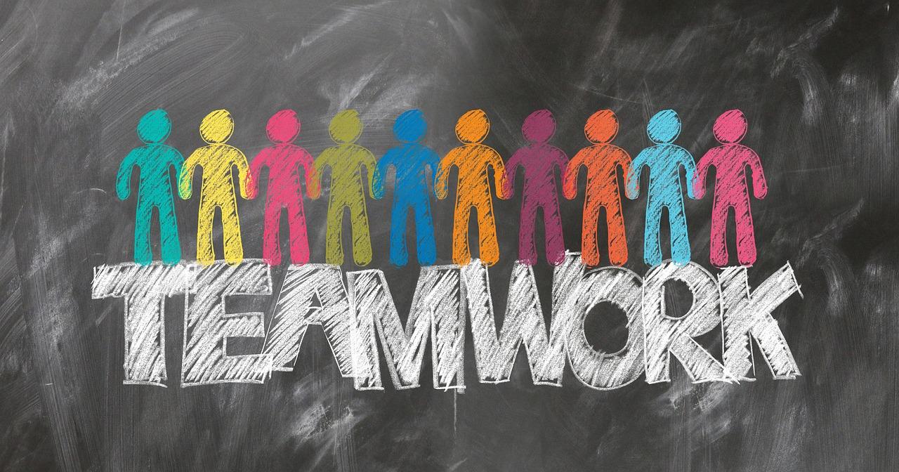 tablica z namalowanym kredą napisem teamwork oraz kolorowymi ludzikami