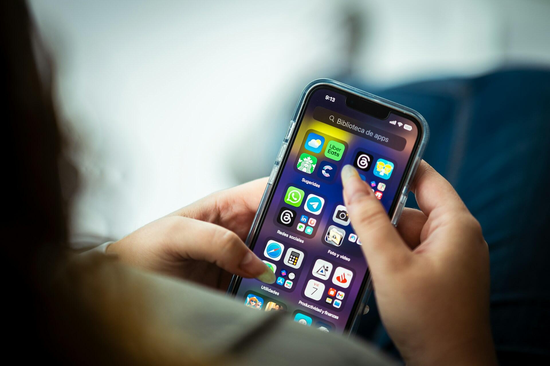 Telefon z aplikacjami na ekranie w dłoniach.