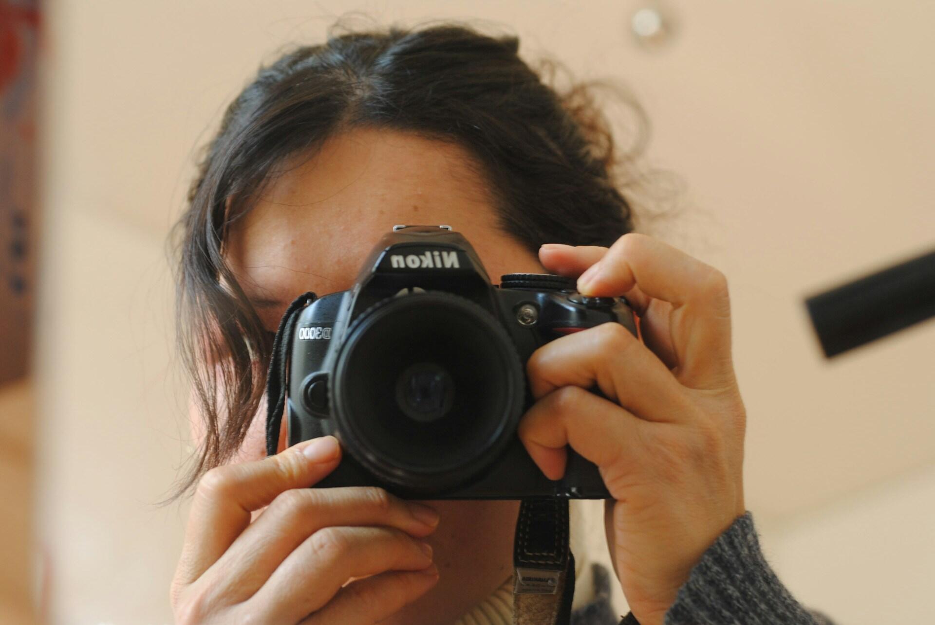 Kobieta z aparatem fotograficznym przy twarzy.